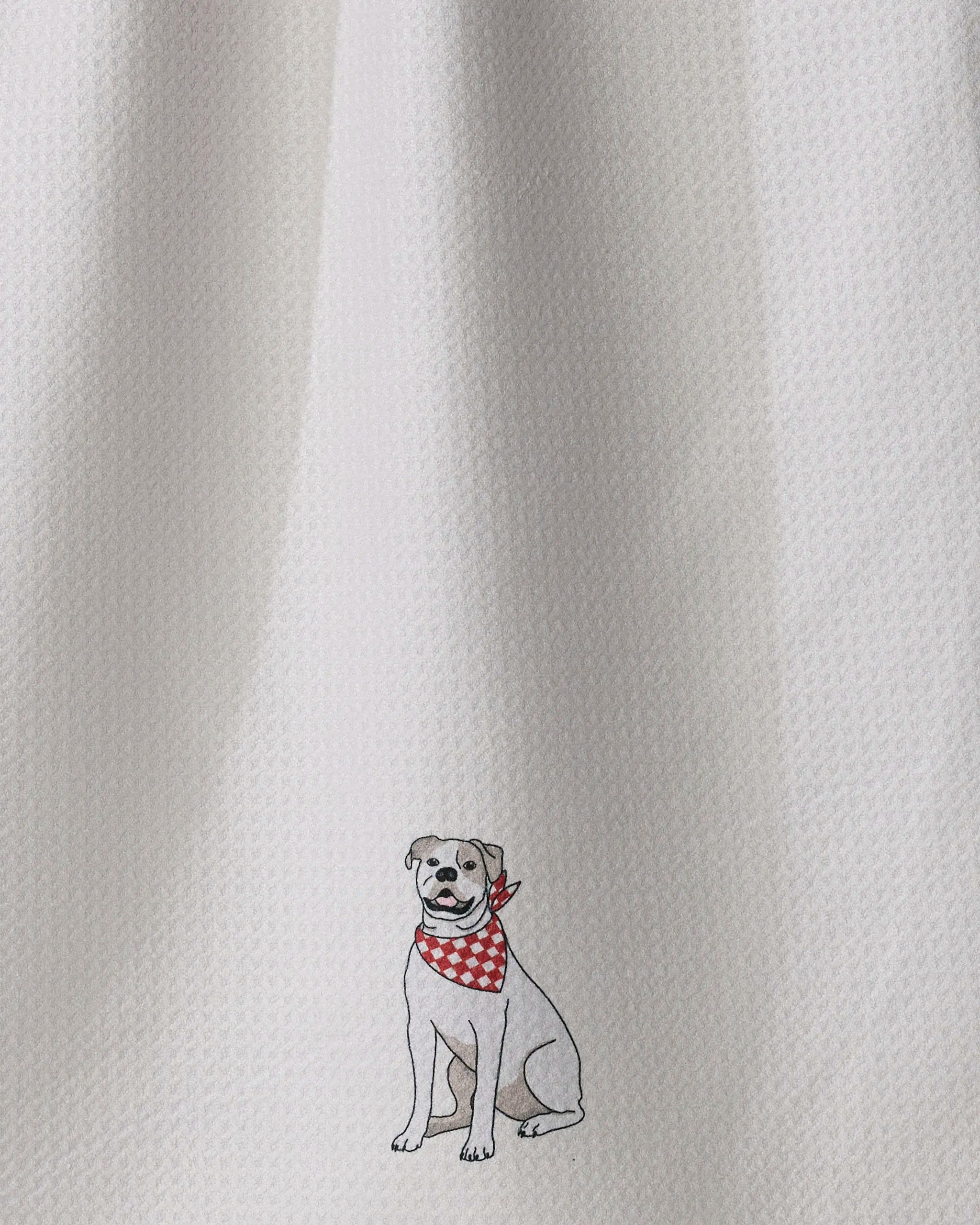 The “Bulldog Bandana” tea towel by Geometry features a small illustration of a smiling dog in a red and white checkered bandana near the bottom center. This eco-friendly kitchen towel adds charm to your daily routine while being gentle on the environment.