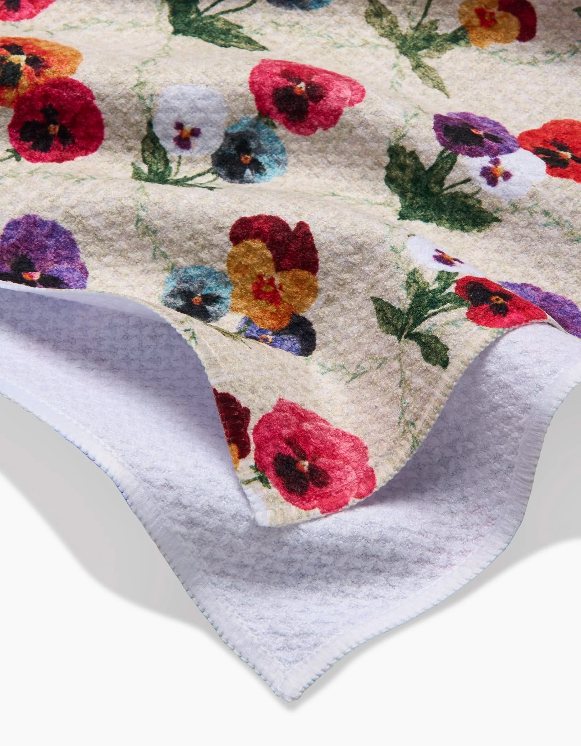 A close-up of Pascale Dilgers Bunch of Pansies Geometry House Tea Towel, showcasing a colorful pansy design on Geoweave fabric and a plain white waffle weave reverse.