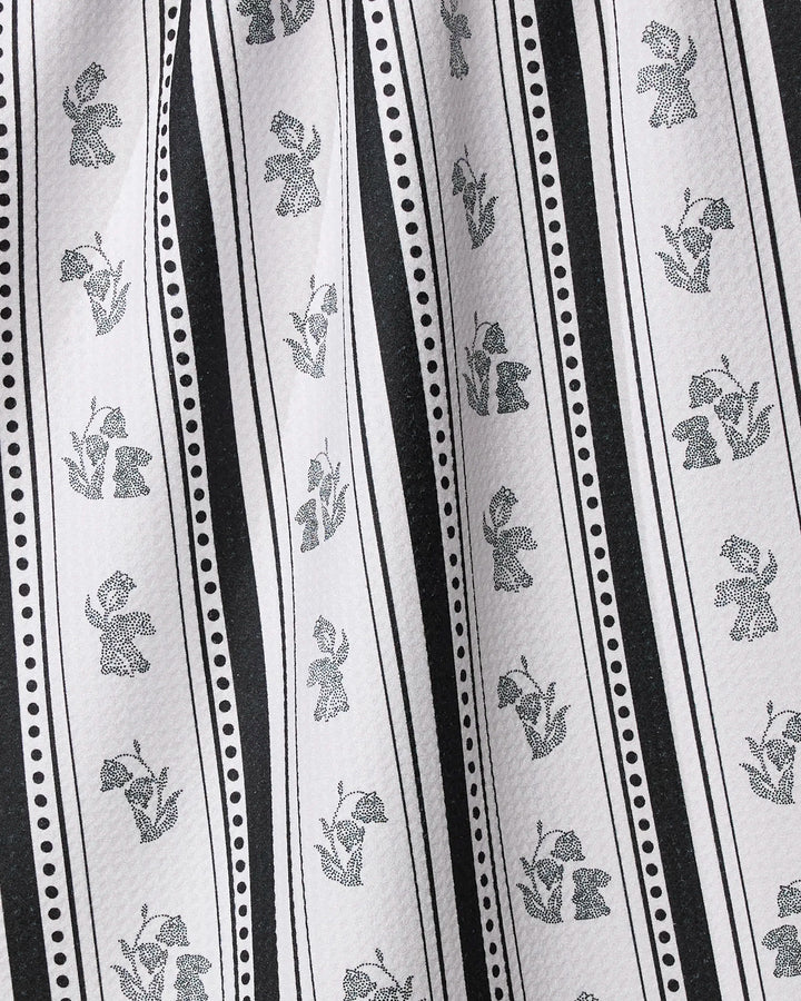 Geometry’s Bunny Dots Stripe kitchen towel features black and white vertical stripes with alternating small flower and tulip patterns, separated by dotted and solid lines. Made from recycled materials, it has a soft texture and gentle folds.