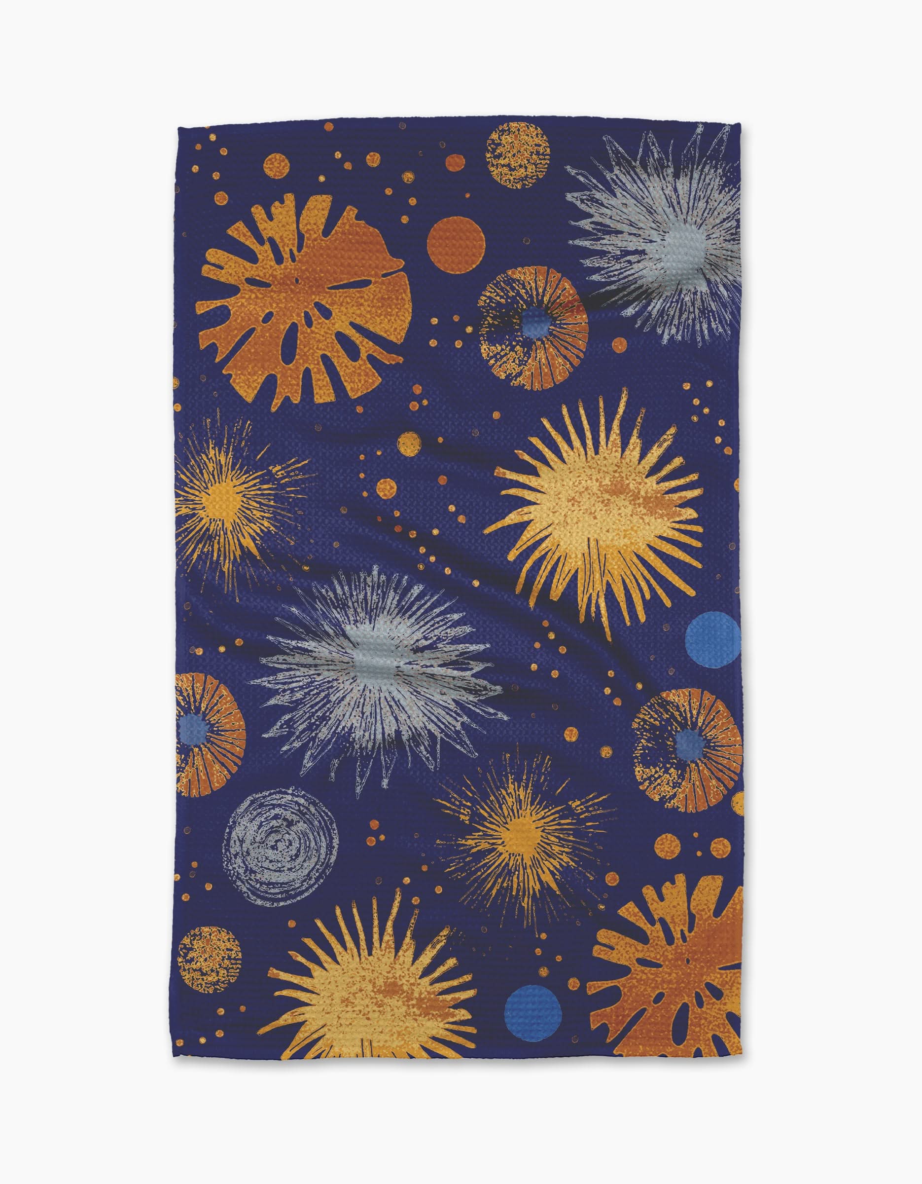 The Geometry Bursting Skies Blue tea towel features a dark blue background with yellow, orange, blue, and gray starburst patterns, resembling fireworks, and is crafted from durable Geoweave fabric.