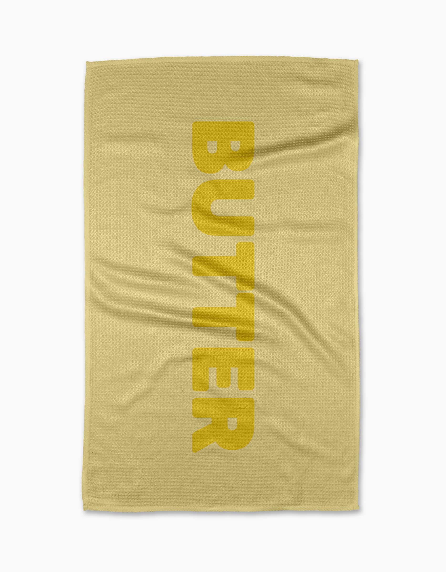 The GEOMETRY Butter yellow tea towel is made from Geoweave fabric, printed vertically with BUTTER in bold yellow letters and featuring a subtle textured pattern, shown laid flat on a white background.