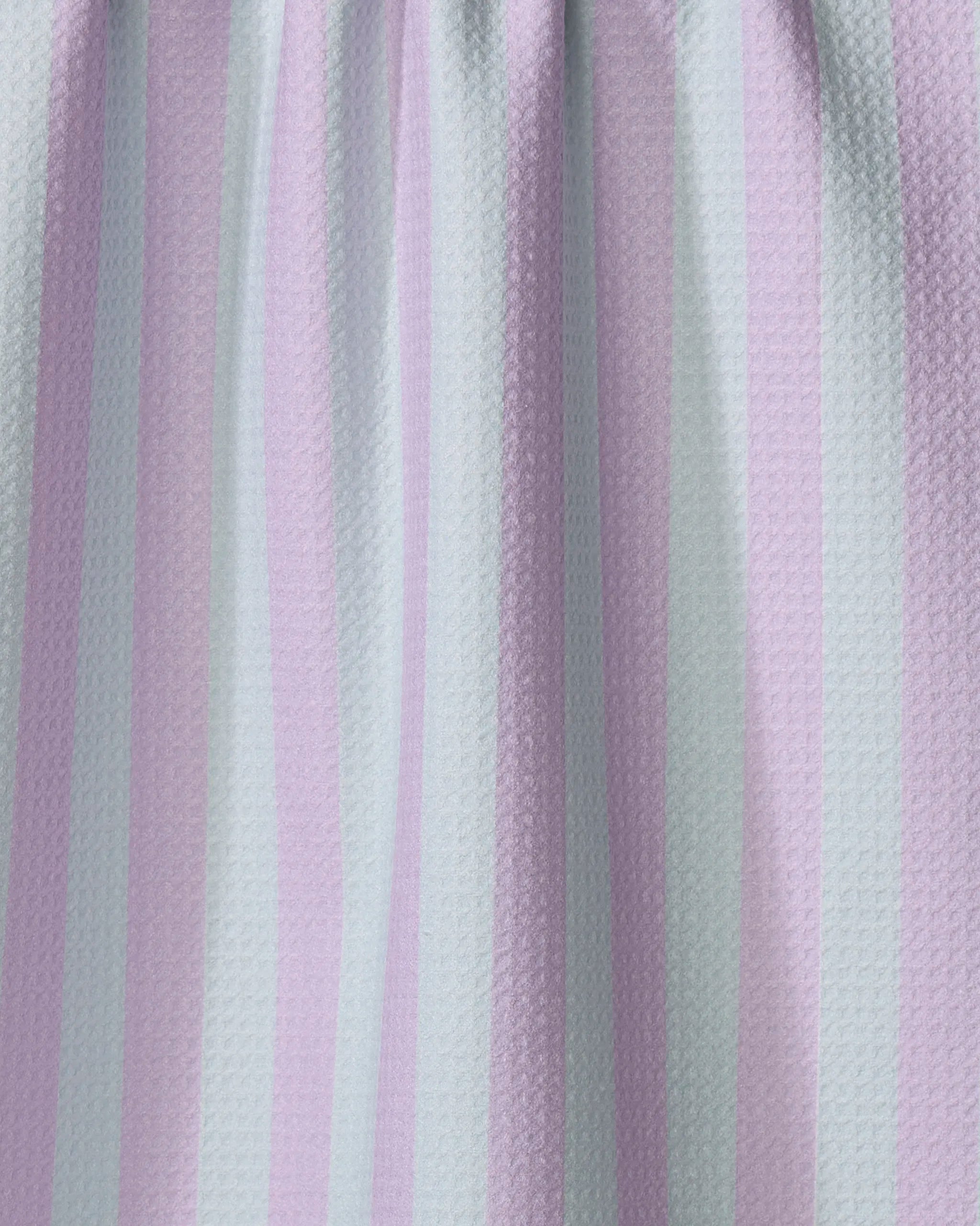 A close-up of The Buy Guide’s Cabana Boy - Mint Lilac kitchen towel shows alternating pastel mint and lilac stripes, a softly textured, puckered surface, and gentle folds at the top.