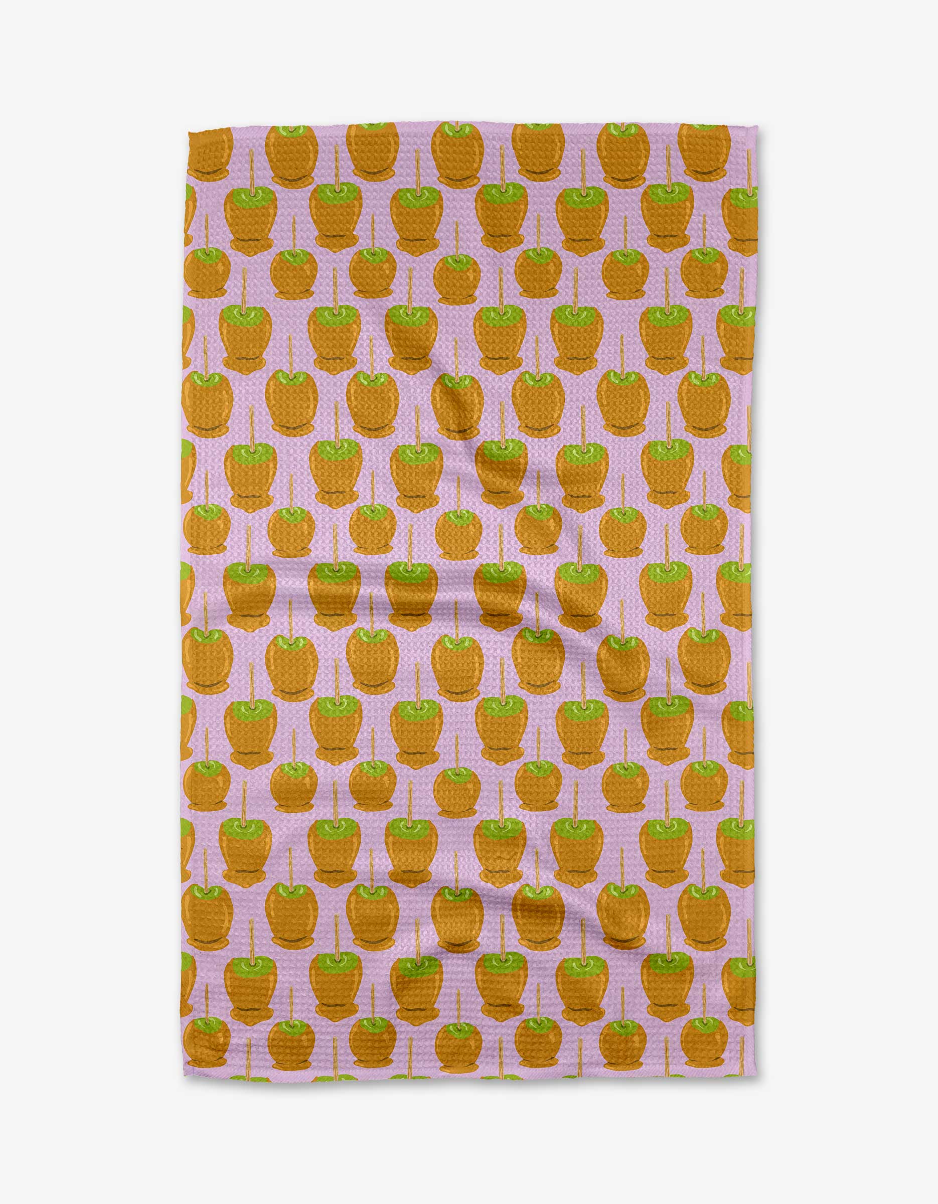 The Caramel Apple tea towel by Elisabeth Wing features a repeating orange apple with green leaf pattern on a light pink background. Made from recycled materials, its fabric is textured and slightly wrinkled.