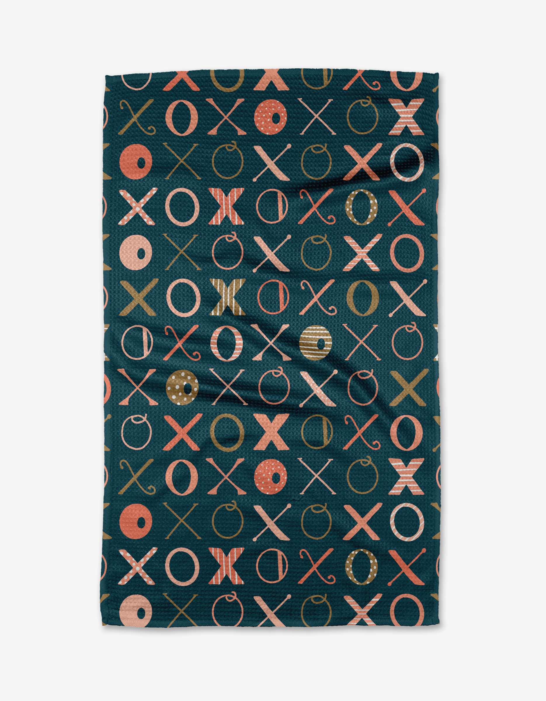 The Carys Navy tea towel by Amy MacCready is made from recycled materials and features a dark teal base with a repeating X and O pattern in orange, pink, and tan—some O’s have stripes or dots.