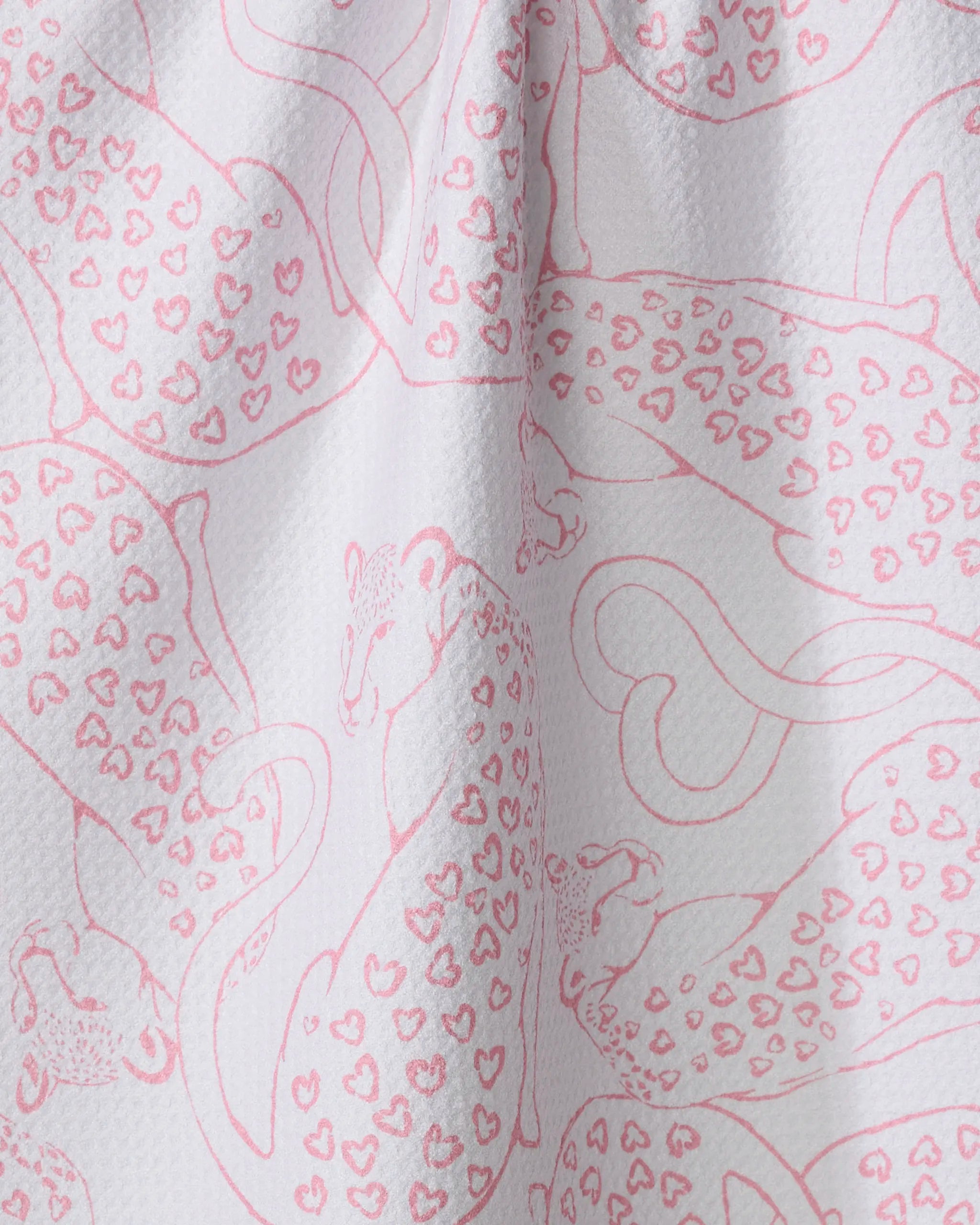 Close-up of Hufton Studio’s Cat Lover recycled kitchen towel, featuring a white fabric with pink leopards in heart-shaped spots. The towel has a slightly textured surface and visible folds.