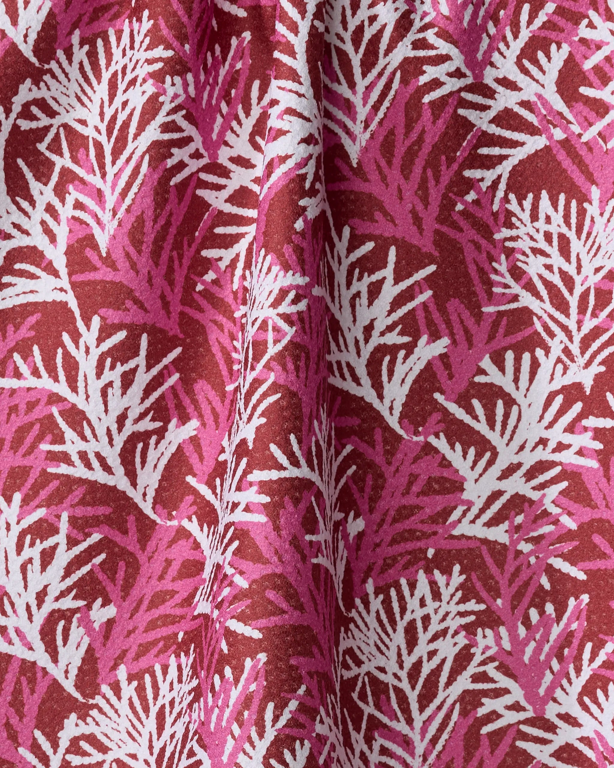 A close-up of the Cedar Pine ultra-absorbent towel by Kayla Ann, showcasing white and pink coral-like branches on a deep red background for a vibrant, textured look.