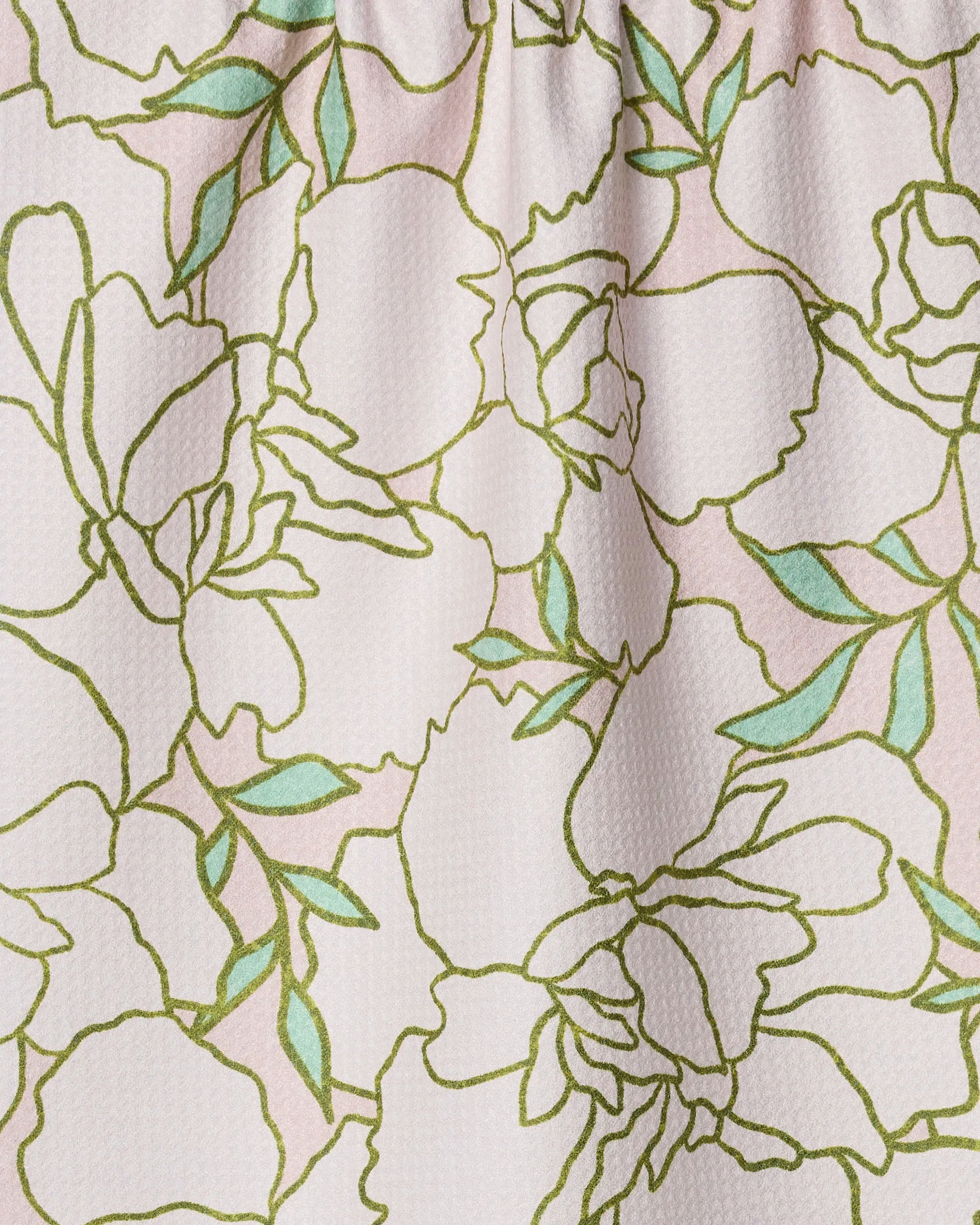 Close-up of the Celecia kitchen towel by Amy MacCready, showing a floral pattern with green leaves and outlined flowers on a light pink background. Made from recycled materials, the fabric has gentle folds and a subtly raised texture.