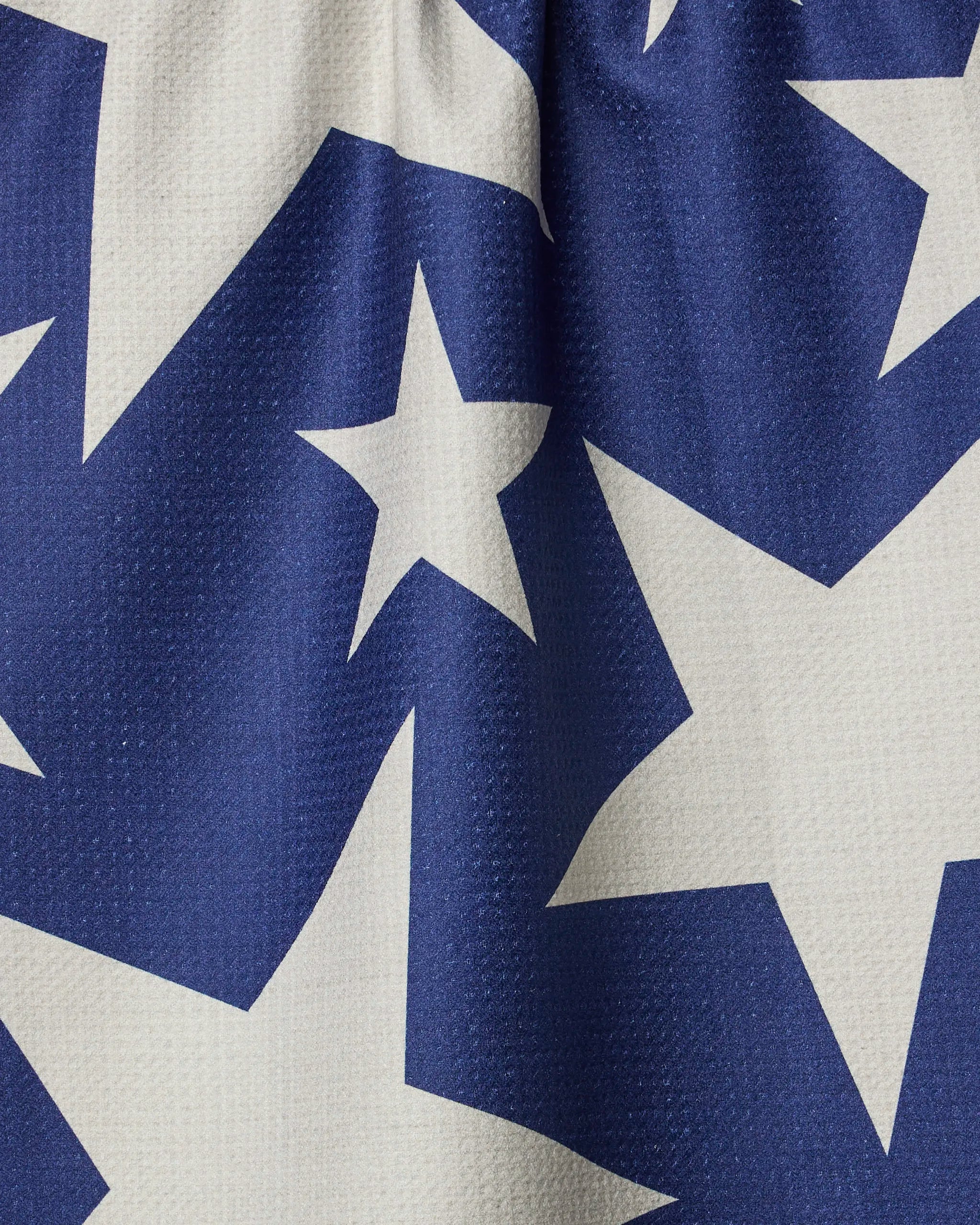A close-up of Celeste by Geometry, featuring blue textured fabric with large white stars reminiscent of the American flag—ideal for a tea towel or recycled kitchen towel.