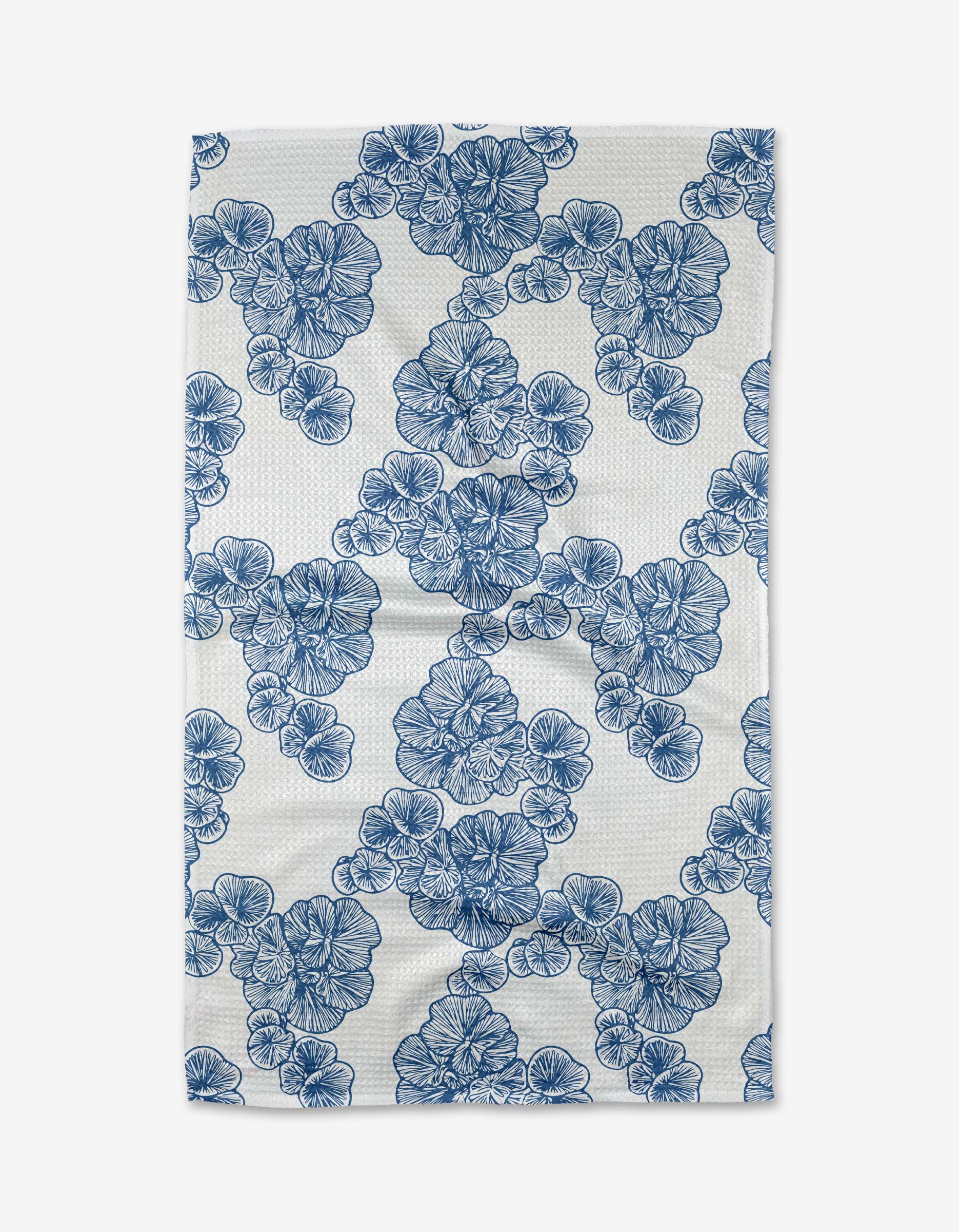 The Celia tea towel from Second Nature Studio is a rectangular, ultra-absorbent white towel made from recycled materials, featuring a repeating blue floral pattern with diagonally arranged clusters.