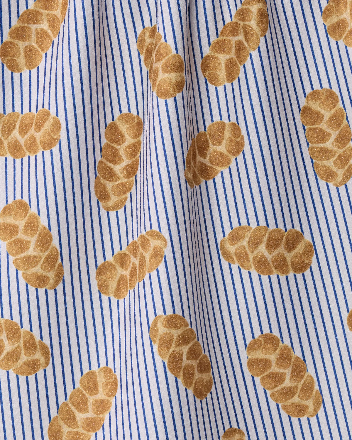 Introducing “Challah Days” by Geometry—a white tea towel adorned with blue vertical stripes and a repeating diagonal pattern of braided challah loaves. This eco-friendly towel combines charm and practicality, making it a delightful addition to your kitchen décor.