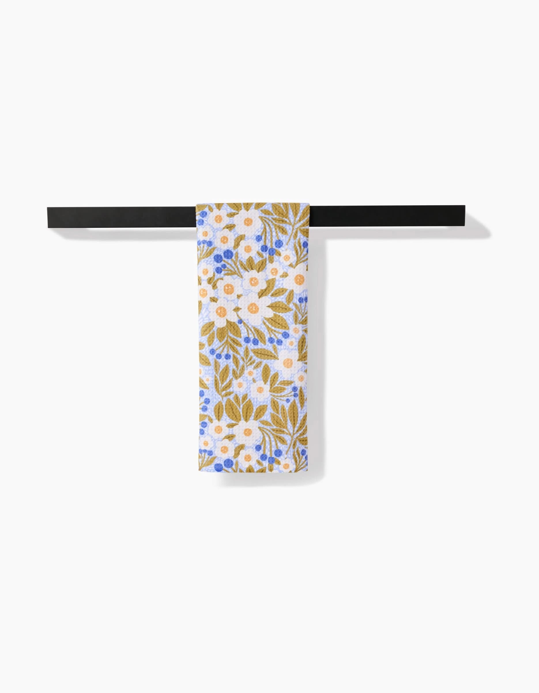 A Lisa Nelson Chamomile And Blue tea towel featuring yellow, white, and blue florals hangs on a black bar. Made with ultra-absorbent Geoweave™ fabric, it pops against the plain white background.