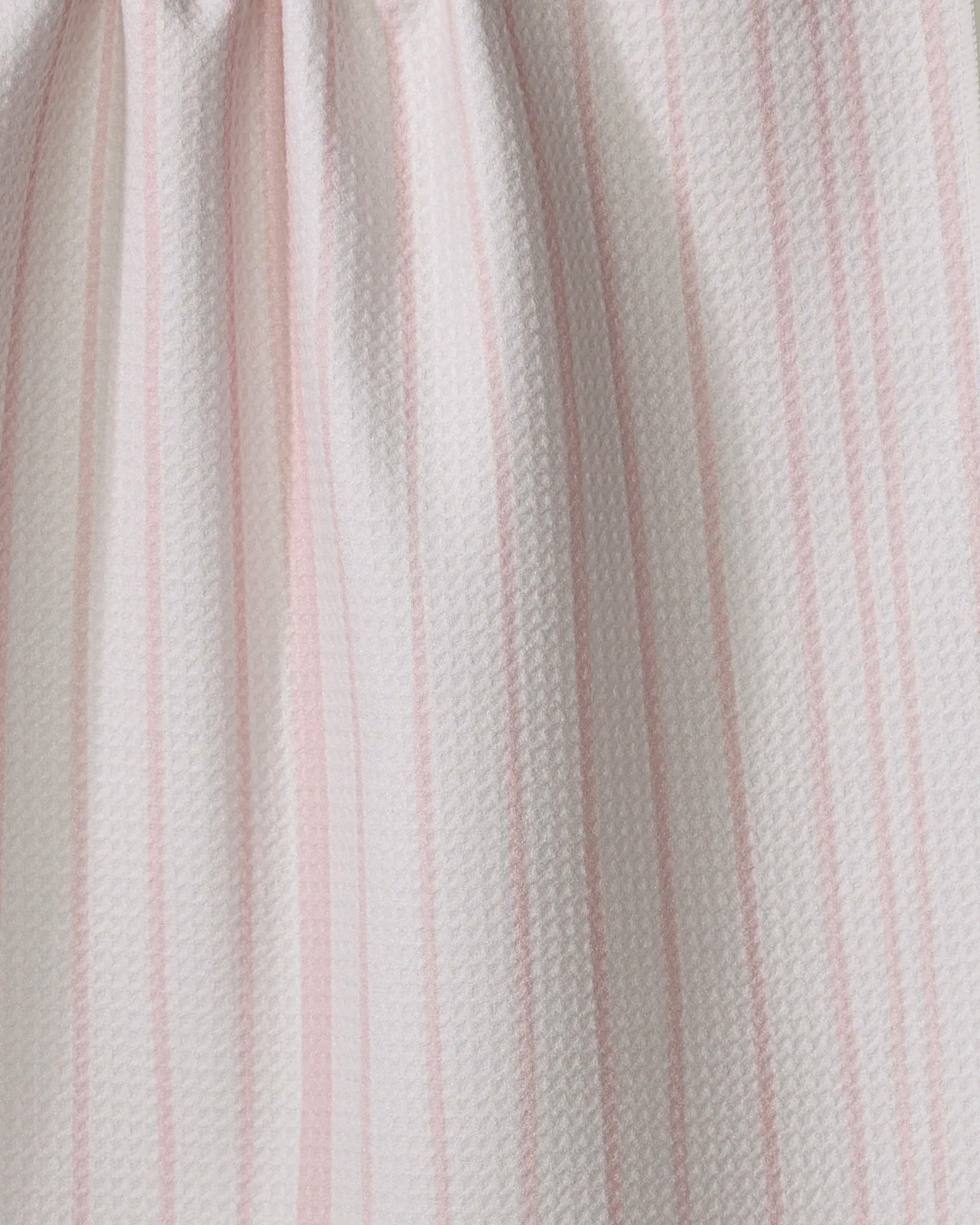 A close-up of the Becki Owens Charlotte Stripe tea towel, featuring white textured fabric with vertical pink stripes and slight gathering at the top, designed for ultra absorbency in the kitchen.