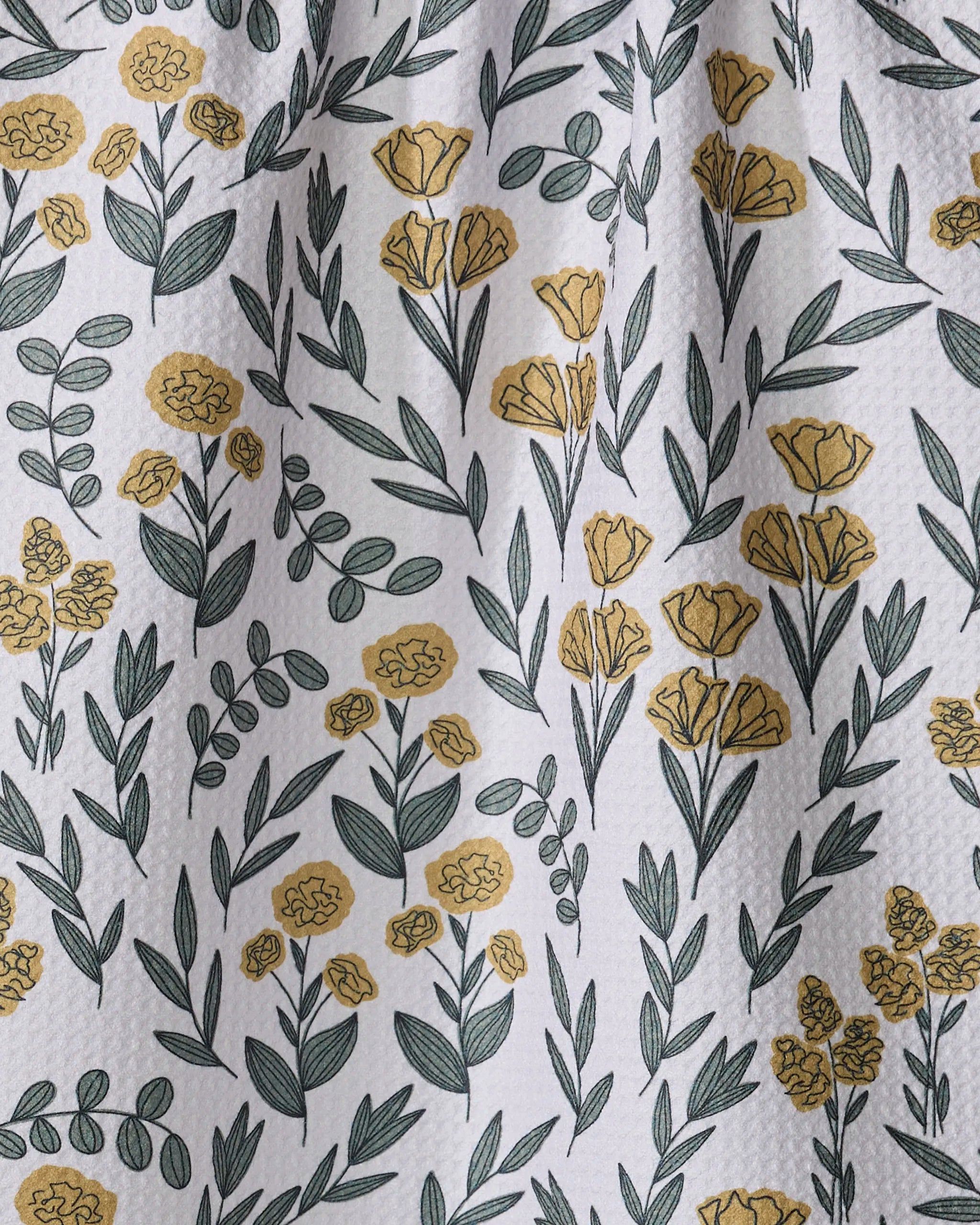 The Charolette Yellow kitchen towel by Charlie Rowan Designs features a recycled white fabric adorned with a scattered pattern of yellow flowers and green leaves in various sizes.