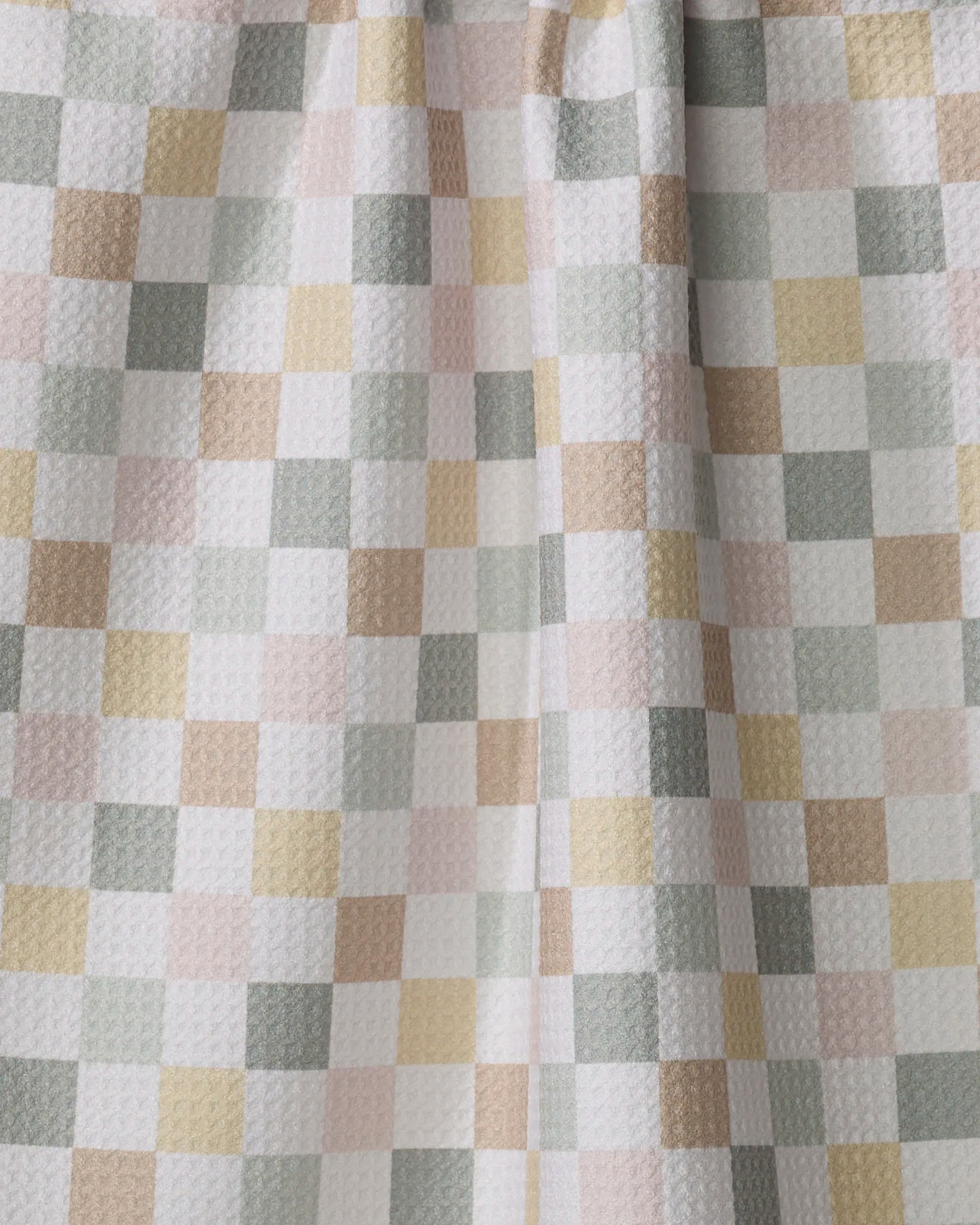 A close-up of Kelsi Fullmer’s “Check Me Out” tea towel, crafted from recycled materials with a textured feel and a checkered pattern in soft pastel white, pink, yellow, green, and beige.