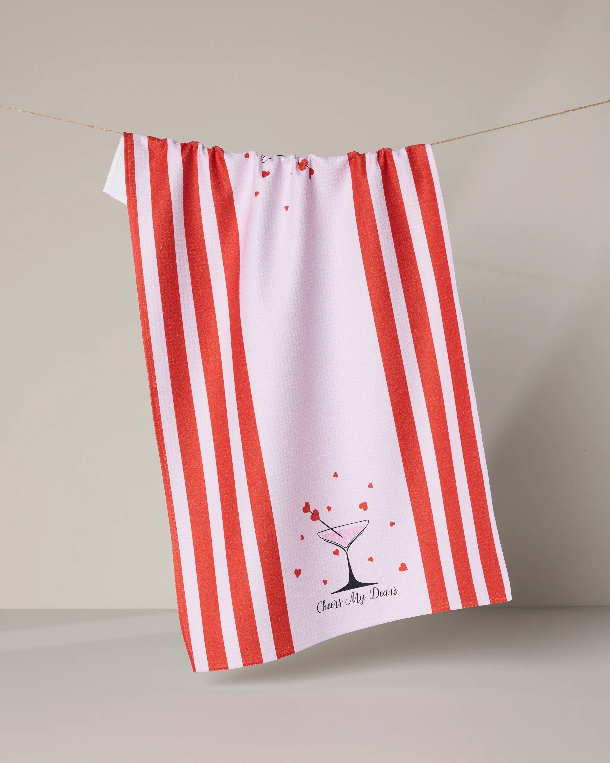 The Geometry Cheers My Dears tea towel, made from recycled materials, features bold red stripes, a martini glass with red hearts, and "Cheers, My Dears" printed below.
