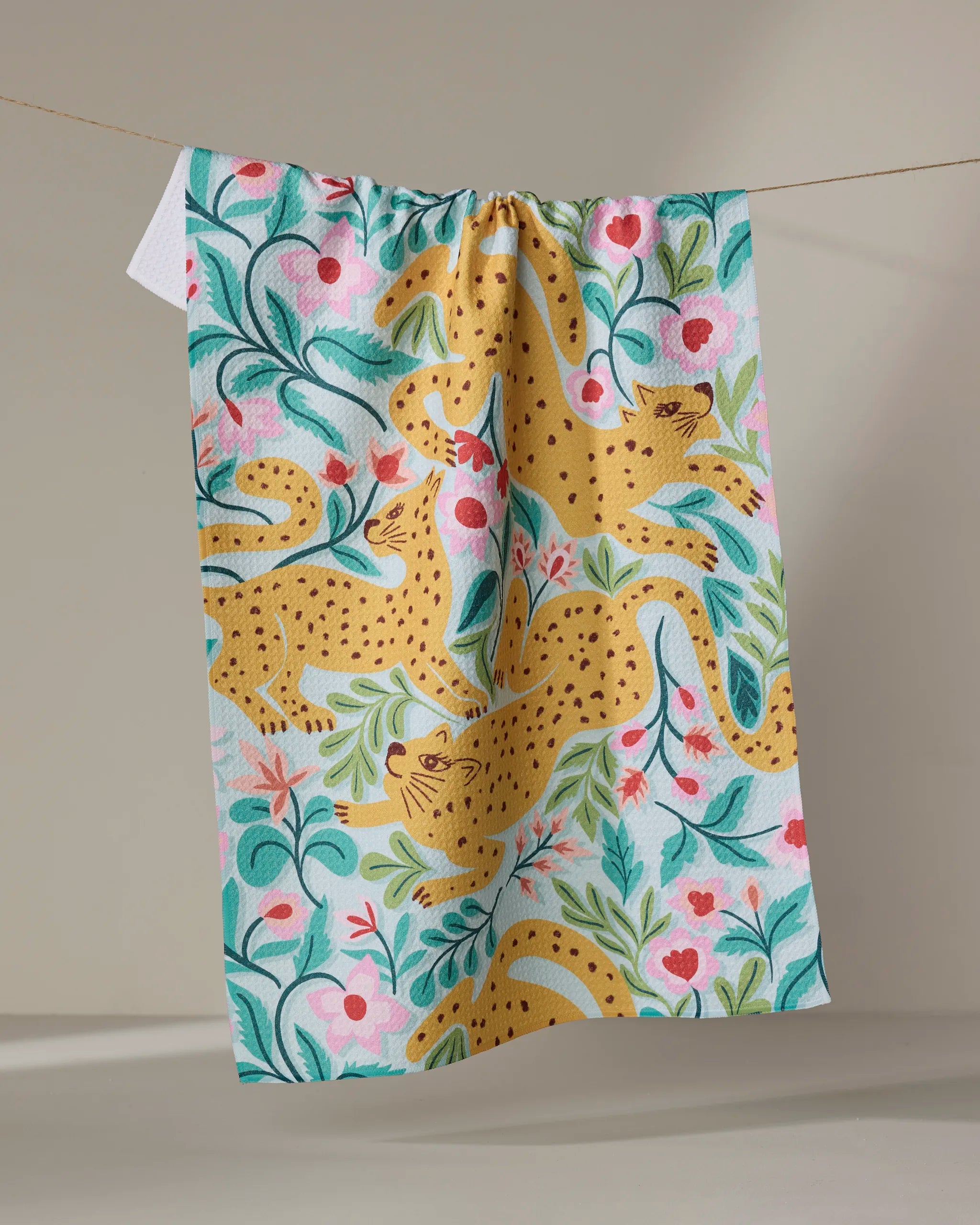 The Cheetah Haven kitchen towel by Jasmine Blooms Designs features yellow leopards, pink flowers, and green leaves, adding eco-friendly charm and vibrant style to your space.