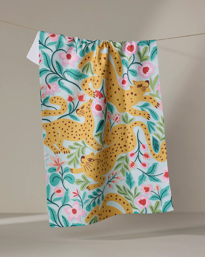 The Cheetah Haven kitchen towel by Jasmine Blooms Designs features yellow leopards, pink flowers, and green leaves, adding eco-friendly charm and vibrant style to your space.