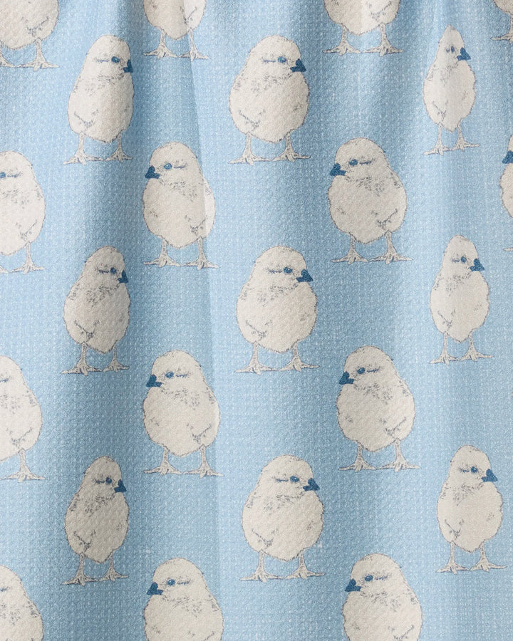 The Geometry Chickadee tea towel features a light blue background with white chicks patterned evenly throughout, accented with blue detailing on their beaks and eyes. Charming and ultra-absorbent, it’s perfect for any kitchen.