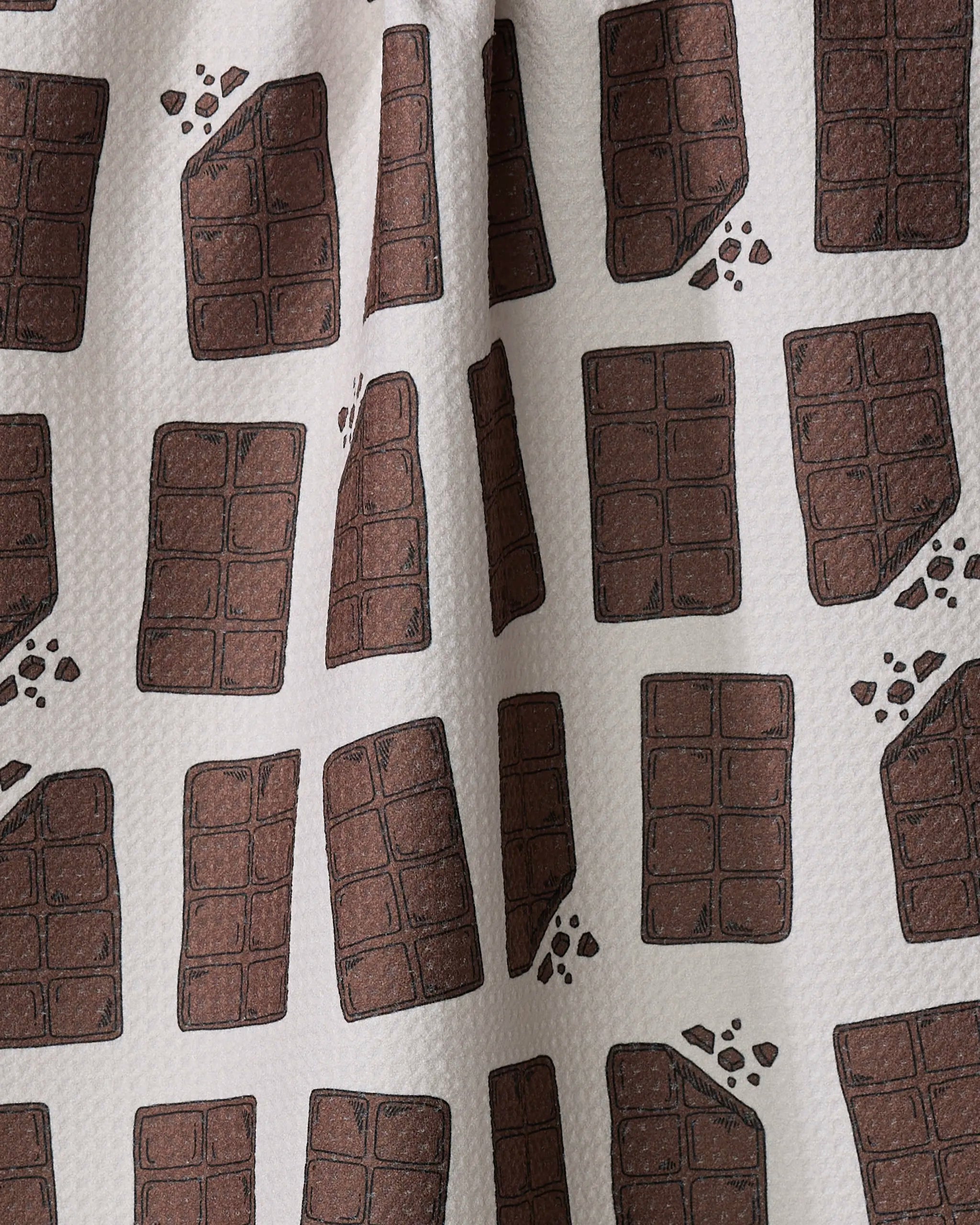 The "Chocolate Everything" tea towel by Amy Droubay features charming illustrations of chocolate bars and pieces on a light background, making this ultra-absorbent towel both stylish and practical for any kitchen.
