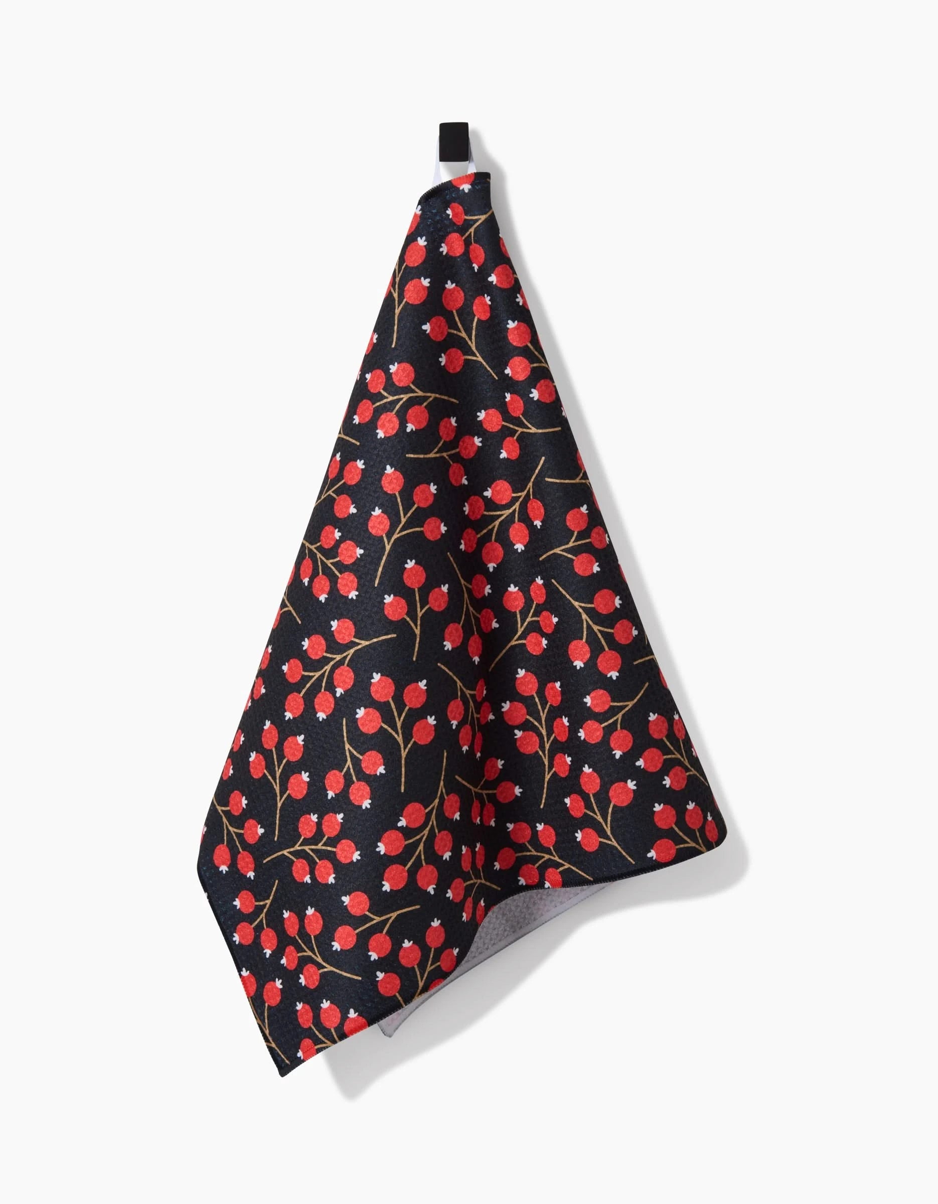 The Christmas Berries recycled kitchen towel by Megan Kampa features a dark base with small red cherries and green stems, hanging from a black loop against a white background.