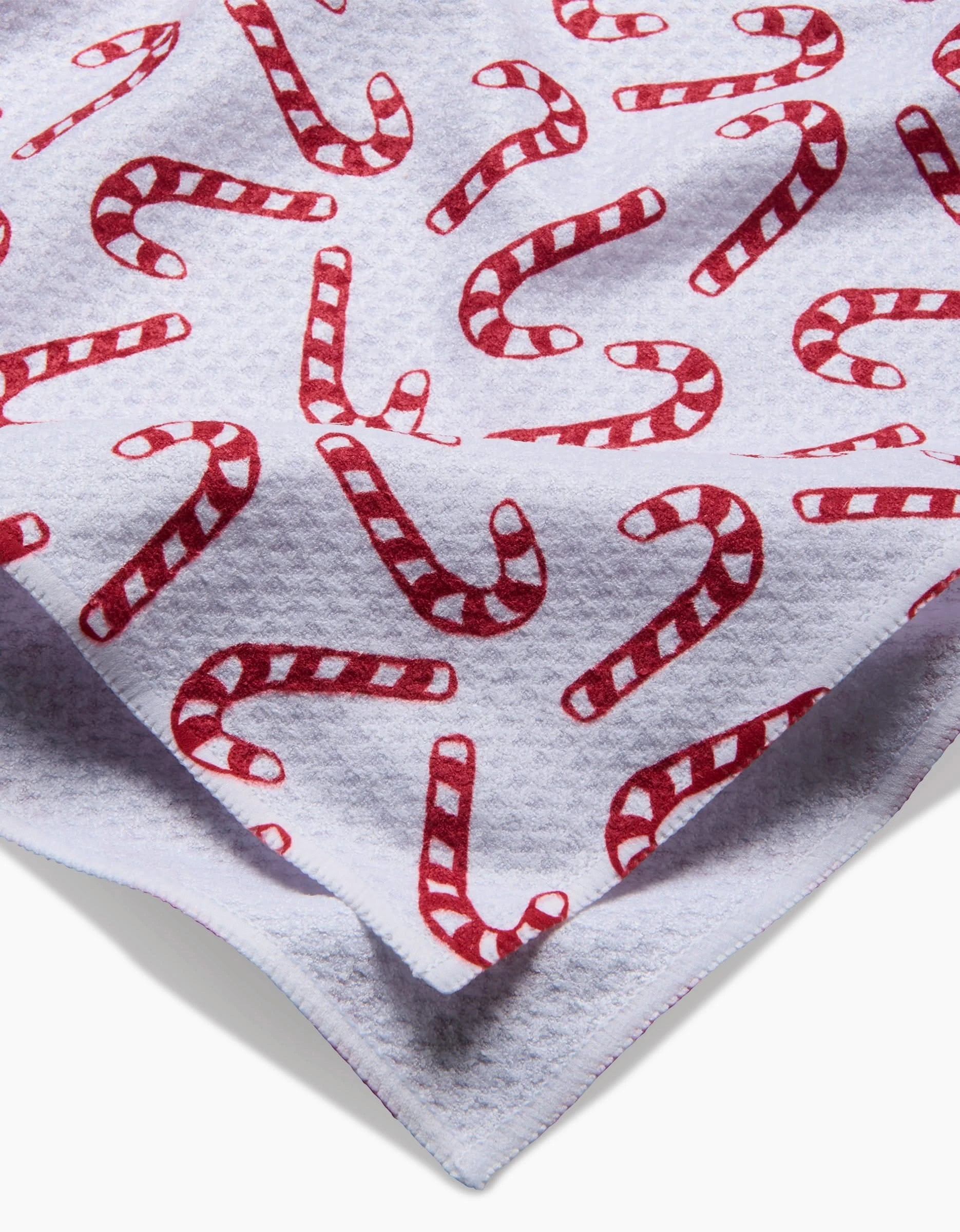 Aubrey Fairchilds Christmas Candy Canes tea towel features a white textured fabric with red and white candy cane stripes, made from ultra-absorbent recycled materials and shown folded to display both eco-friendly sides.