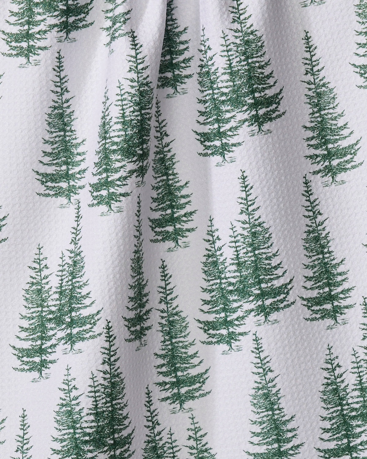 The Aubrey Fairchild "Christmas Forest" tea towel features a white, textured fabric made from recycled materials, with evenly spaced green pine trees in various sizes forming a festive, forest-inspired pattern.