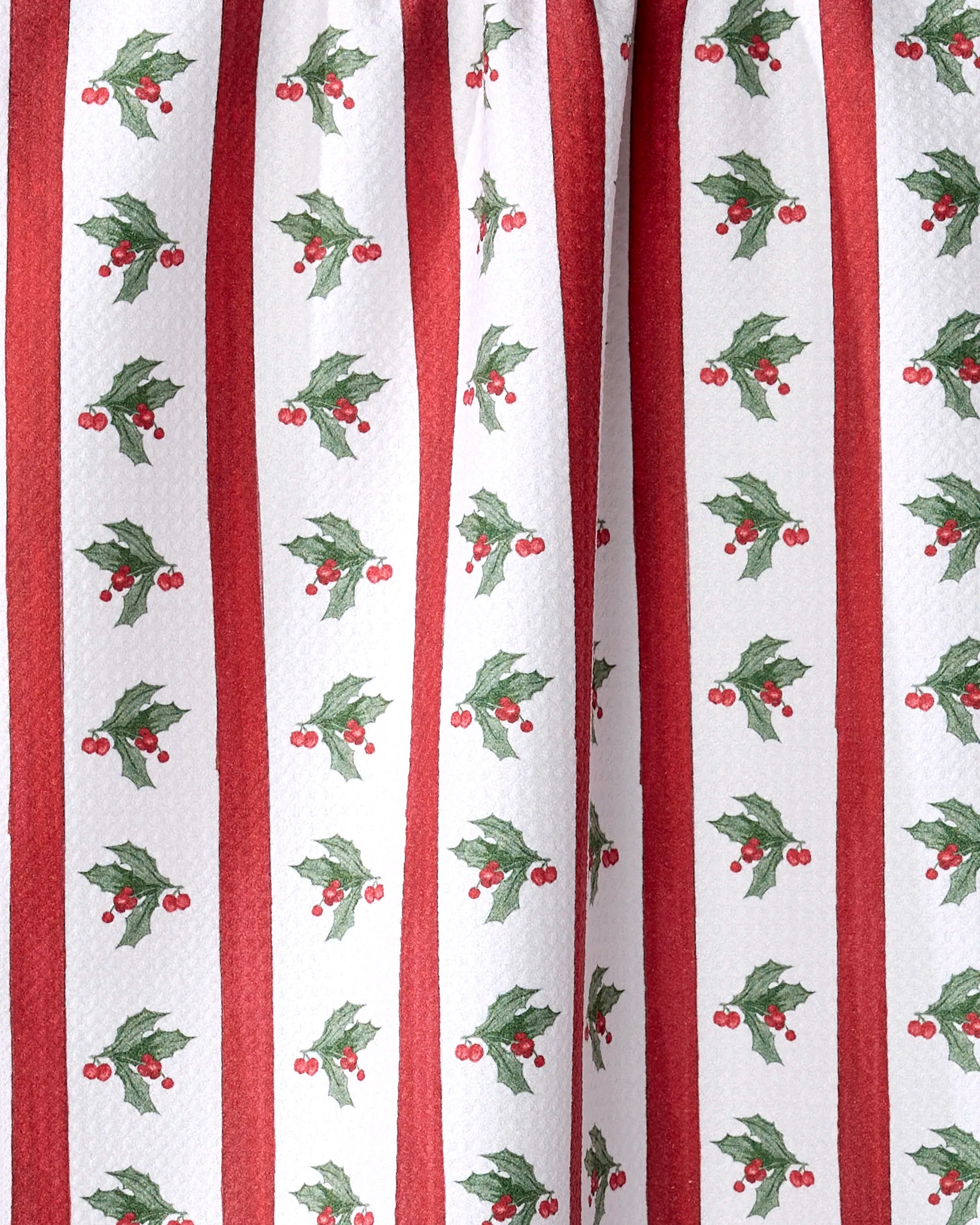 The Aubrey Fairchild Christmas Holly Stripe tea towel features white fabric with vertical red stripes and a festive pattern of green holly leaves and red berries—perfect for adding holiday cheer to your eco-friendly kitchen.