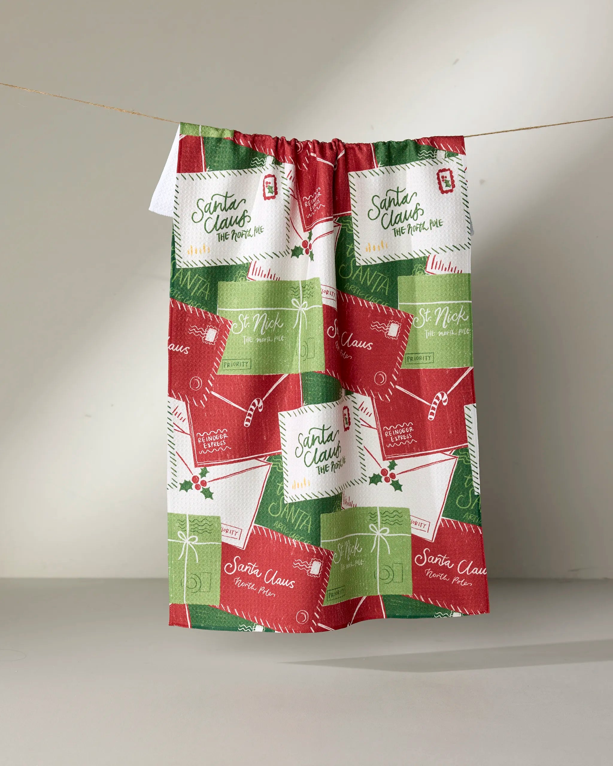 The Christmas Letter Pile curtain by Aubrey Fairchild is made from recycled materials and showcases a festive print of red, green, and white envelopes to Santa and St. Nick, complete with holiday stamps and cheerful accents.