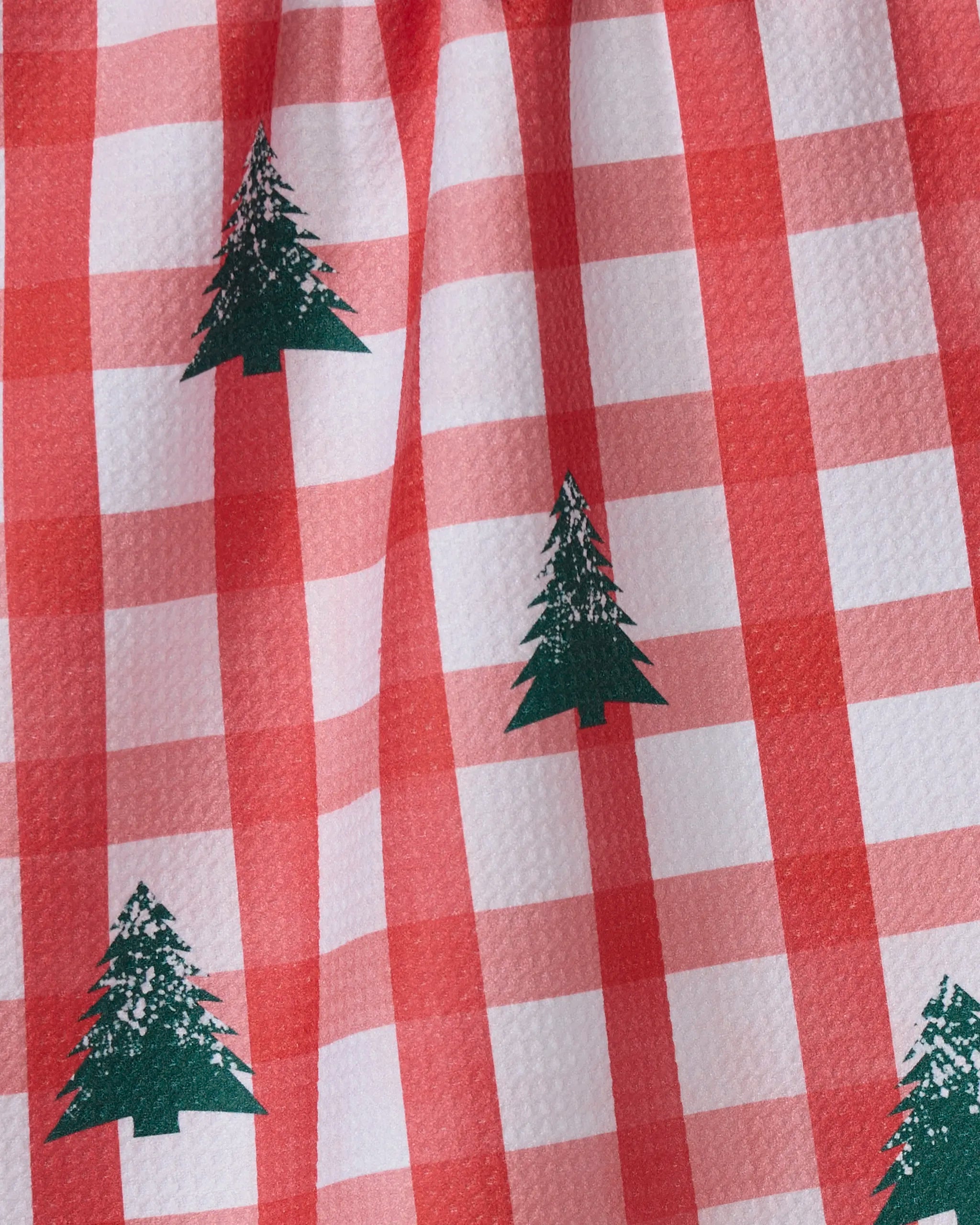 Geometry’s Christmas Pines tea towel boasts a red and white checkered pattern with repeating green pine trees and a slightly wrinkled, ultra-absorbent fabric.