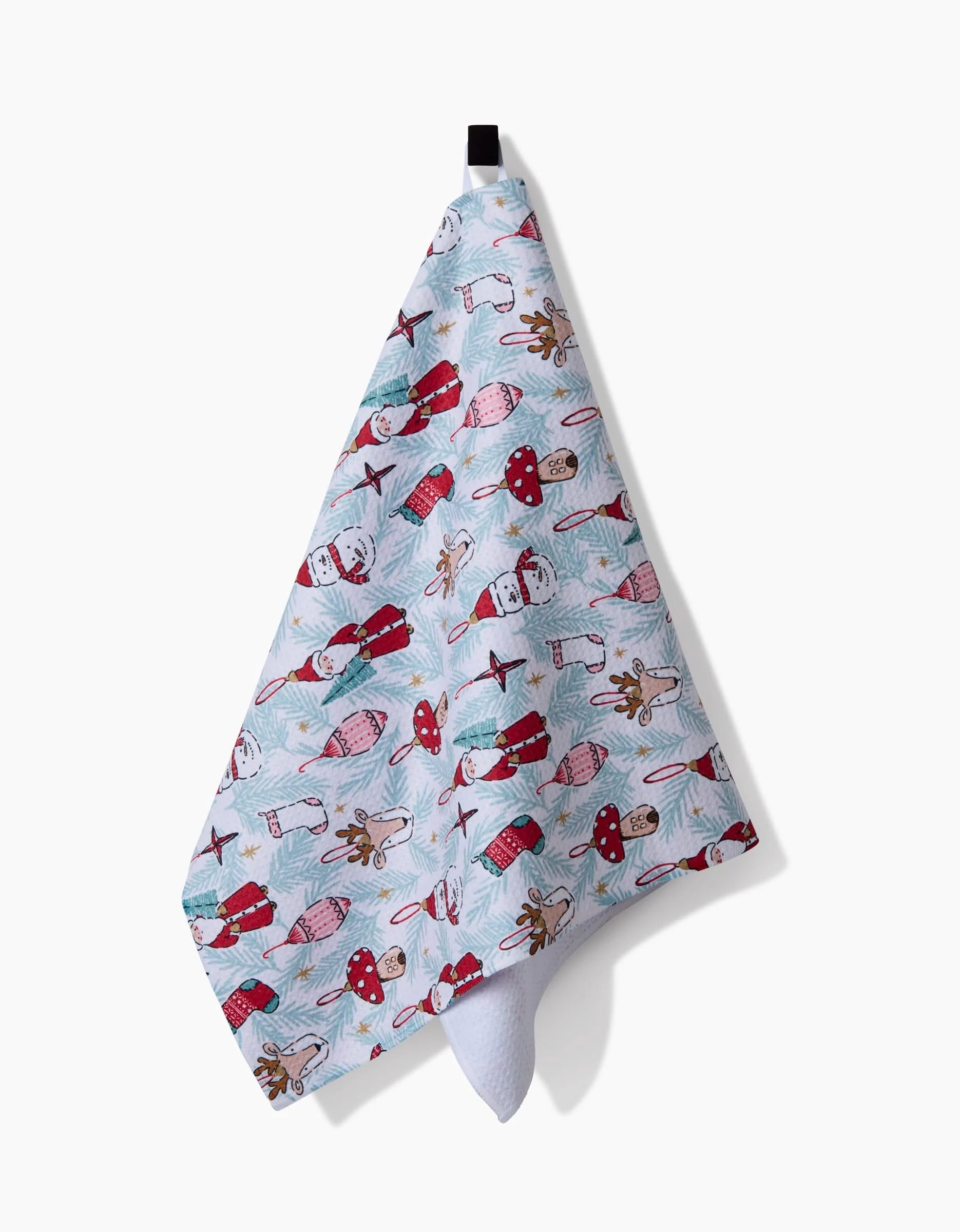 The Christmas Traditions kitchen towel by Hufton Studio, in light blue and featuring Santa Claus, reindeer, sleighs, gifts, and planes illustrations, hangs from a black loop against a white background.