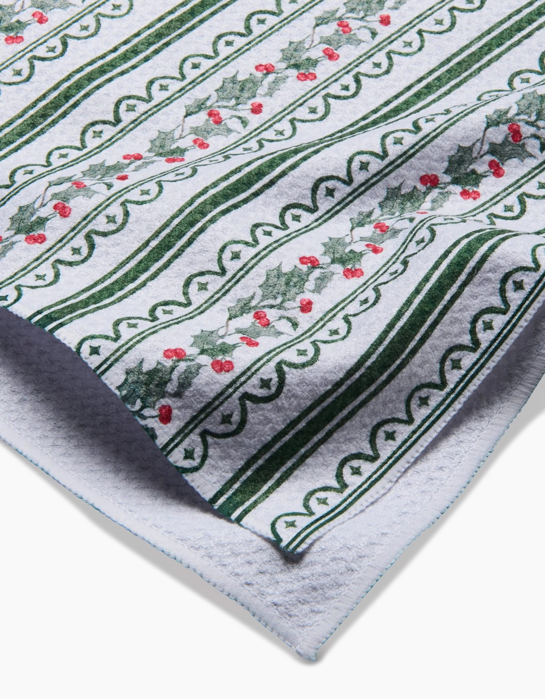 A close-up of the Aubrey Fairchild Christmas Vines ultra-absorbent towel, featuring green stripes and holly leaves with red berries in a repeating festive holiday pattern.