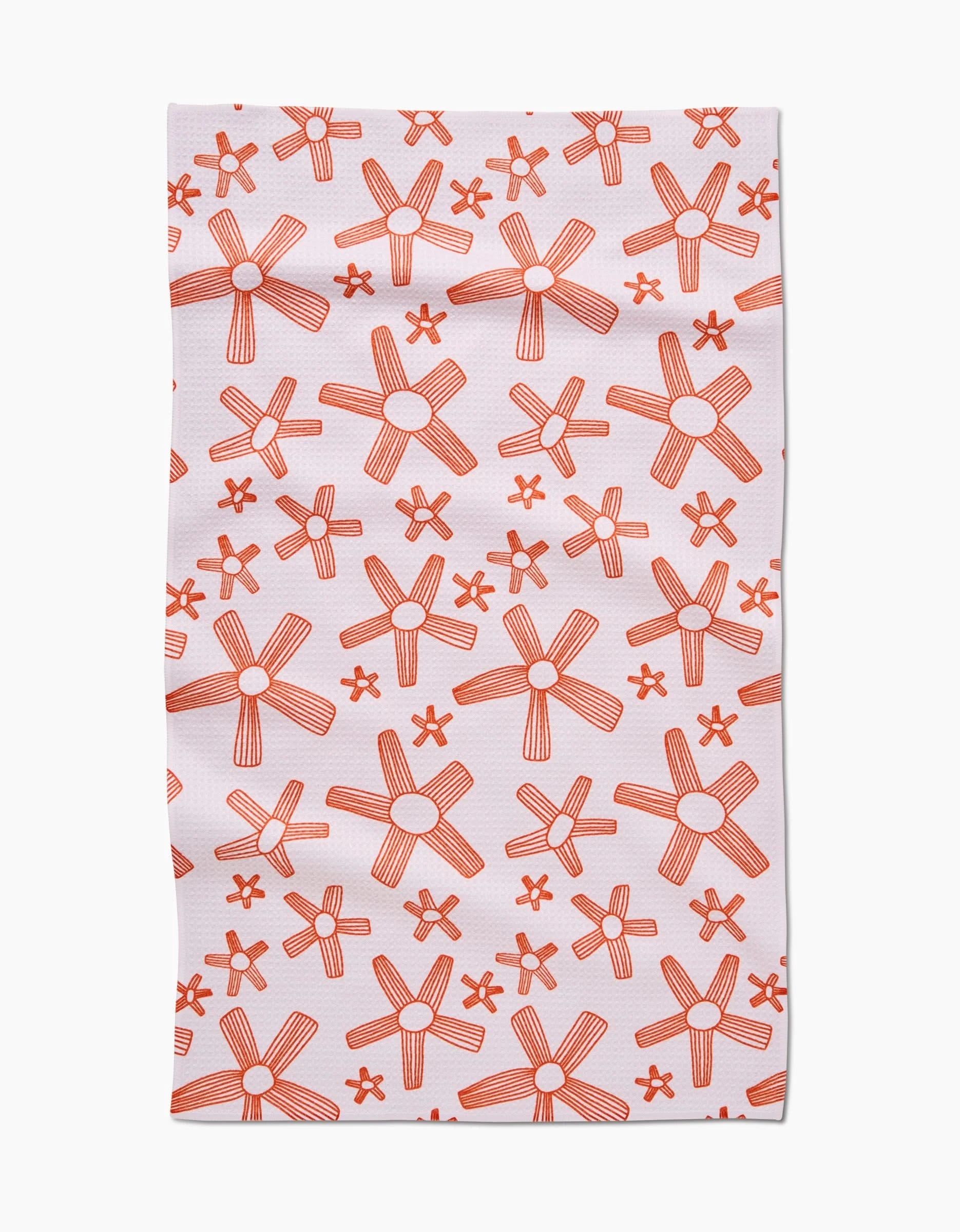 The Chunky Striped Flower Tea Towel by Coit Creative showcases hand-drawn orange star-shaped flowers on white. Its eco-friendly design features recycled materials, a plain background, and slight wrinkles for a stylish, sustainable touch.