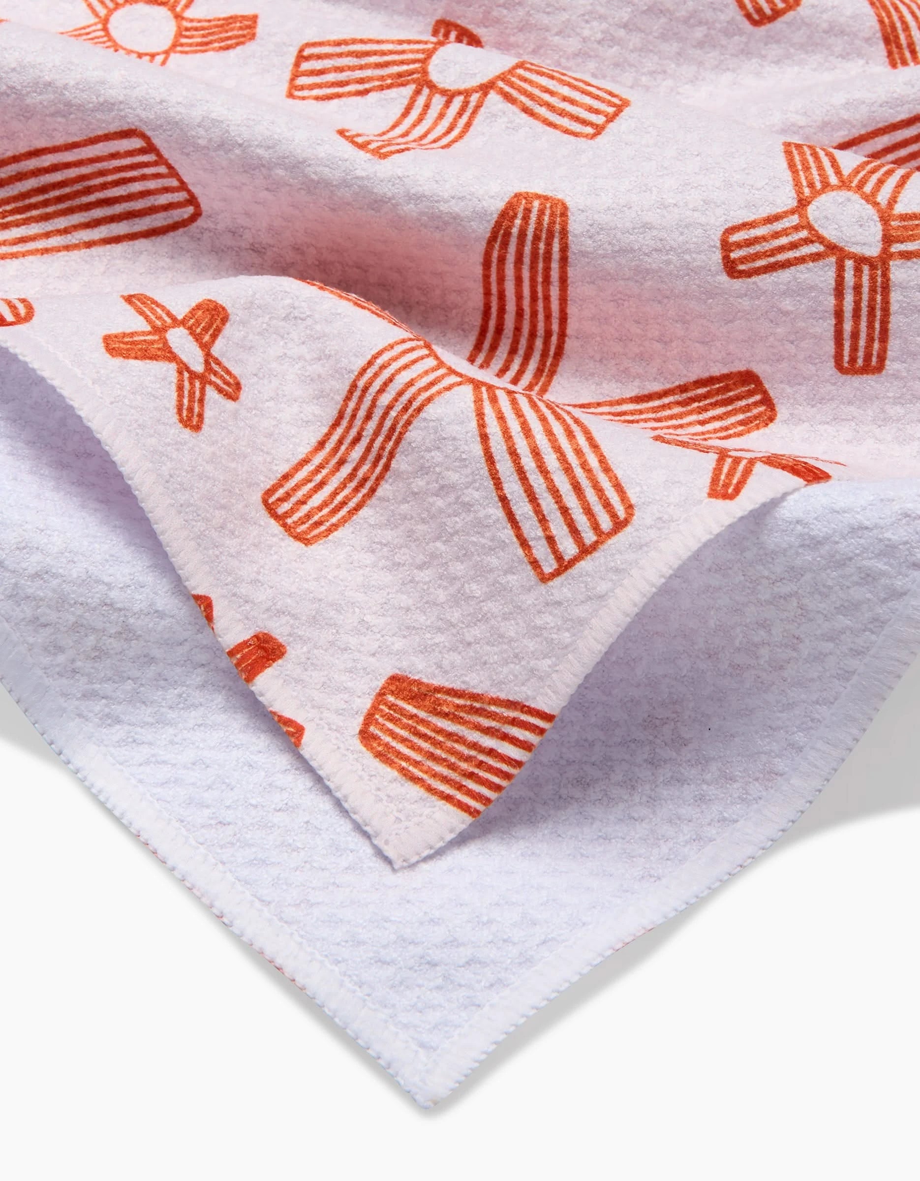 A close-up of Coit Creatives Chunky Striped Flower tea towel, crafted from Geoweave fabric and featuring bold red-orange abstract striped flower patterns. The towel is slightly folded, highlighting its unique texture and vibrant design.