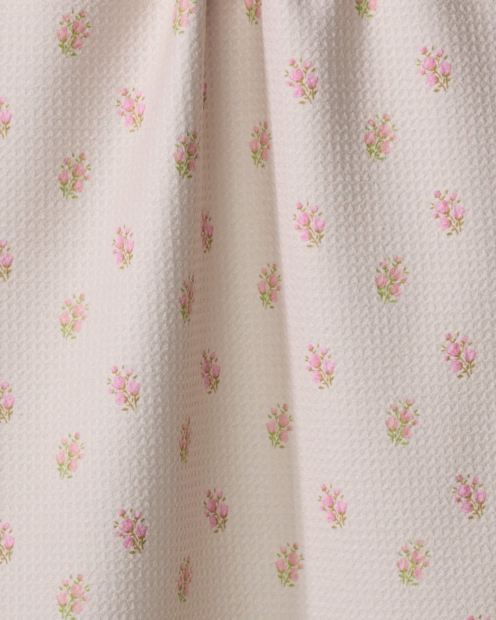 Close-up of Cindy by Kelsi Fullmer—an ultra-absorbent white fabric softly gathered in the center, featuring a repeating pattern of small pink rose bouquets and green leaves, perfect for a charming tea towel.