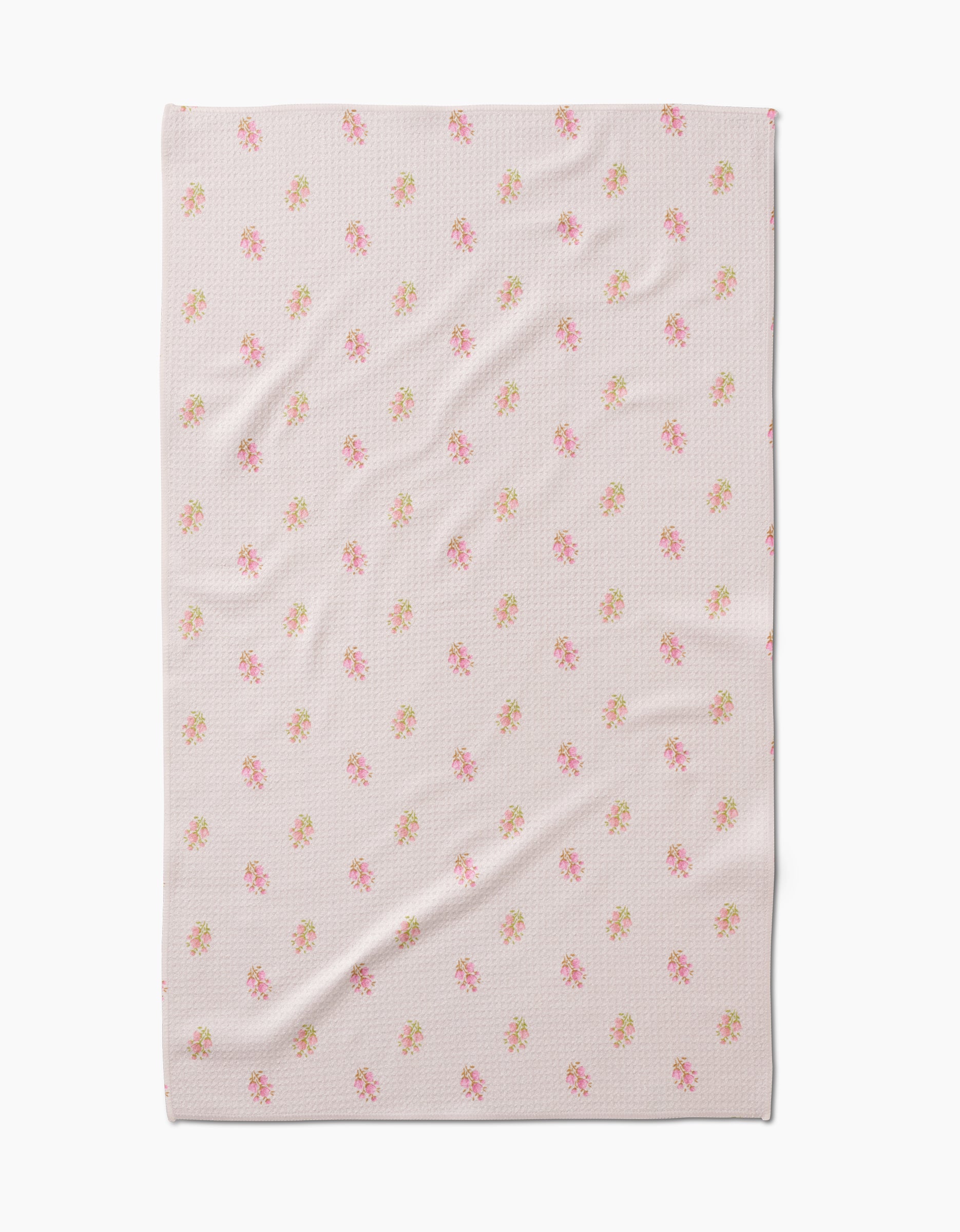 The Cindy blanket by Kelsi Fullmer features a light pink hue, subtle textured pattern, and small pink and green floral motifs. Made from recycled materials, it’s shown laid flat with slight creases.