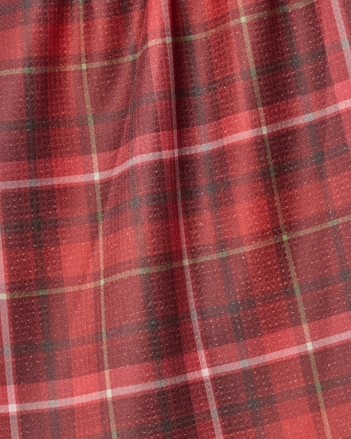Cinnamon Spice by Geometry features a red and black plaid fabric accented with thin white and yellow lines in a classic tartan pattern. This textured material with gentle folds is perfect as a recycled kitchen towel or tea towel, blending style and practicality for your space.