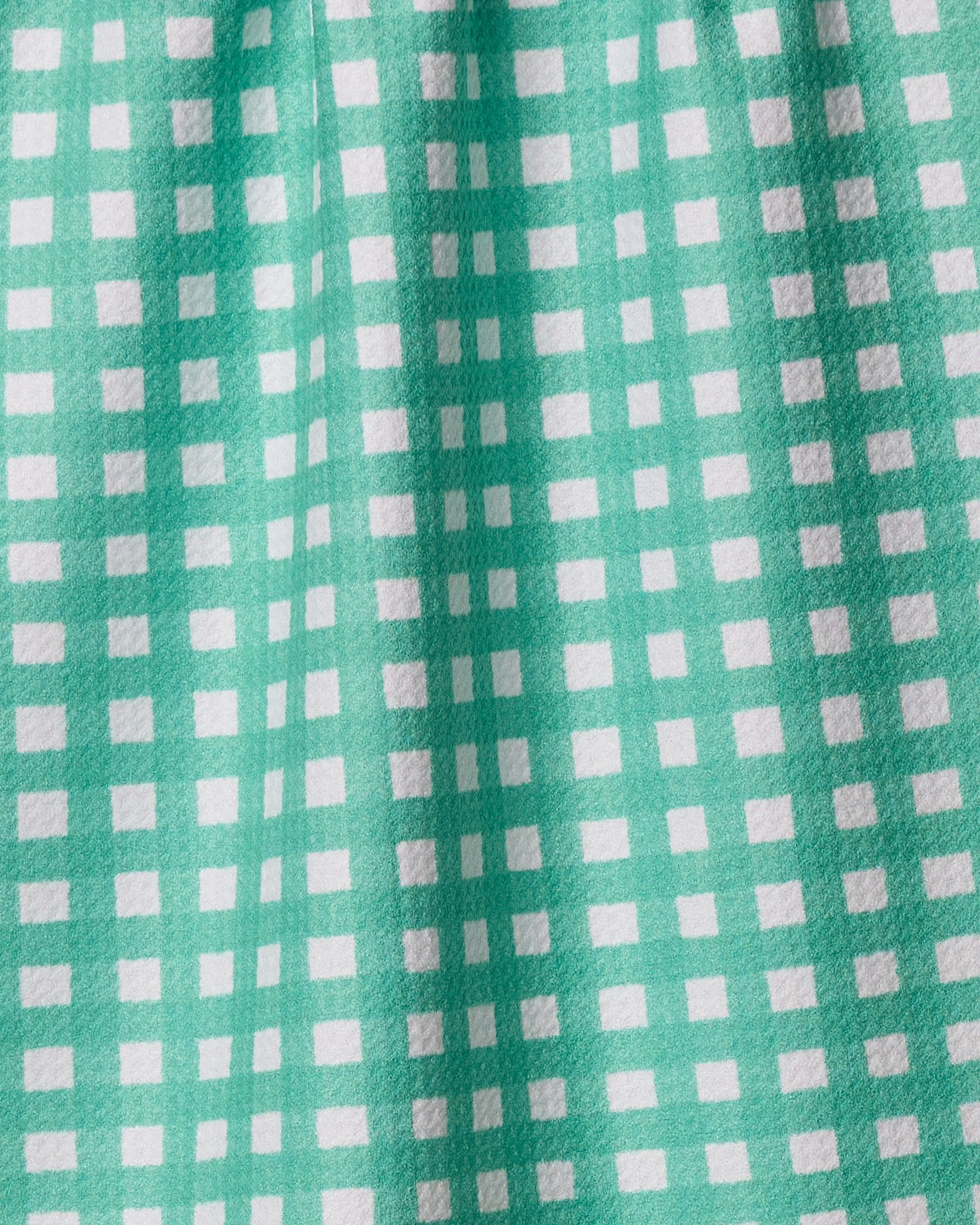 A close-up of Claire by Geometry—a teal tea towel featuring a white checkered pattern. The ultra-absorbent fabric is slightly gathered, creating gentle folds and soft shadows on its stylish kitchen surface.