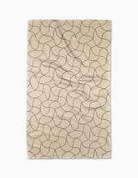 The Gerdadzy Clarity kitchen towel, beige and rectangular with a wavy intersecting brown pattern, made from recycled materials, is shown laid flat with gentle folds on a white background.