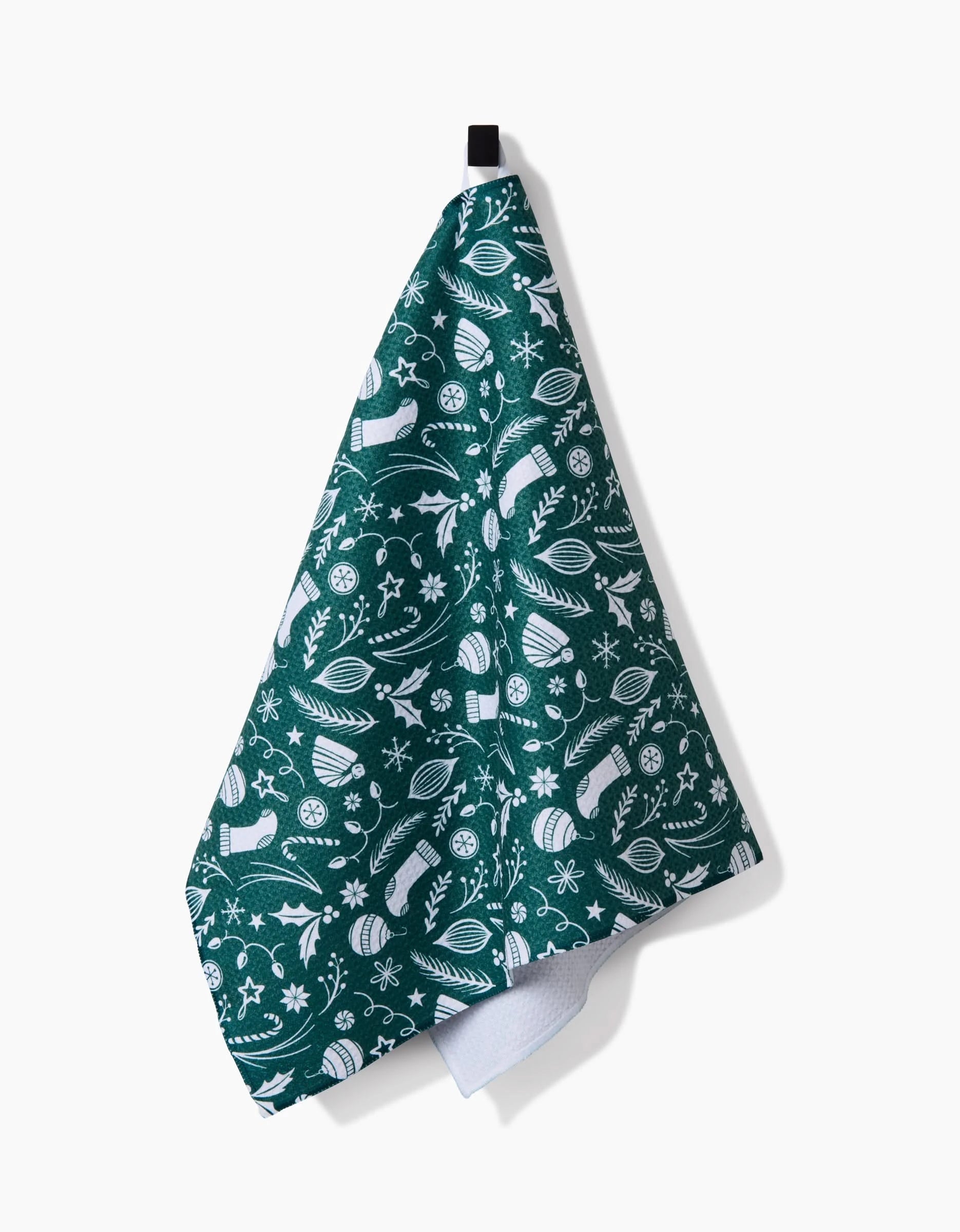 The Classic Christmas Icons Green tea towel by Sarah Daugherty features eco-friendly green and white fabric with outdoor motifs like snowflakes, trees, mittens, and skis, and hangs from a black loop.