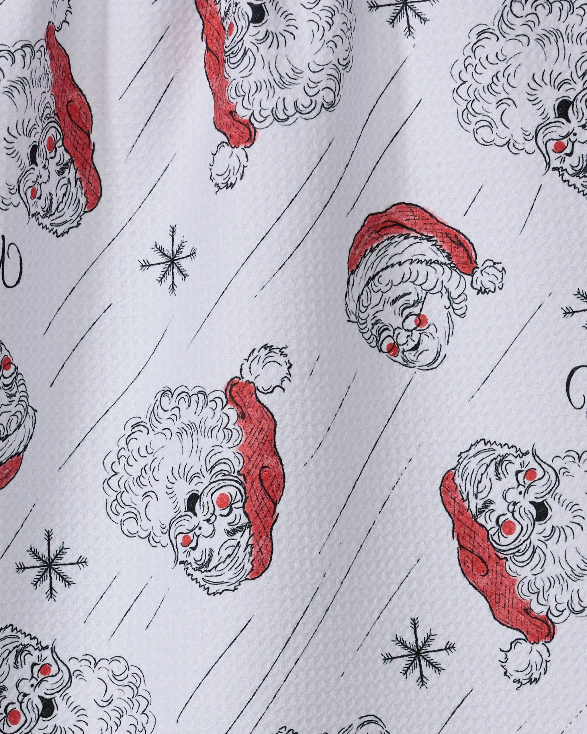 The Geometry "Claus Family Christmas" tea towel features playful Santa Claus faces with red hats, black snowflakes, and wavy lines on white—perfect for adding festive cheer to your kitchen.