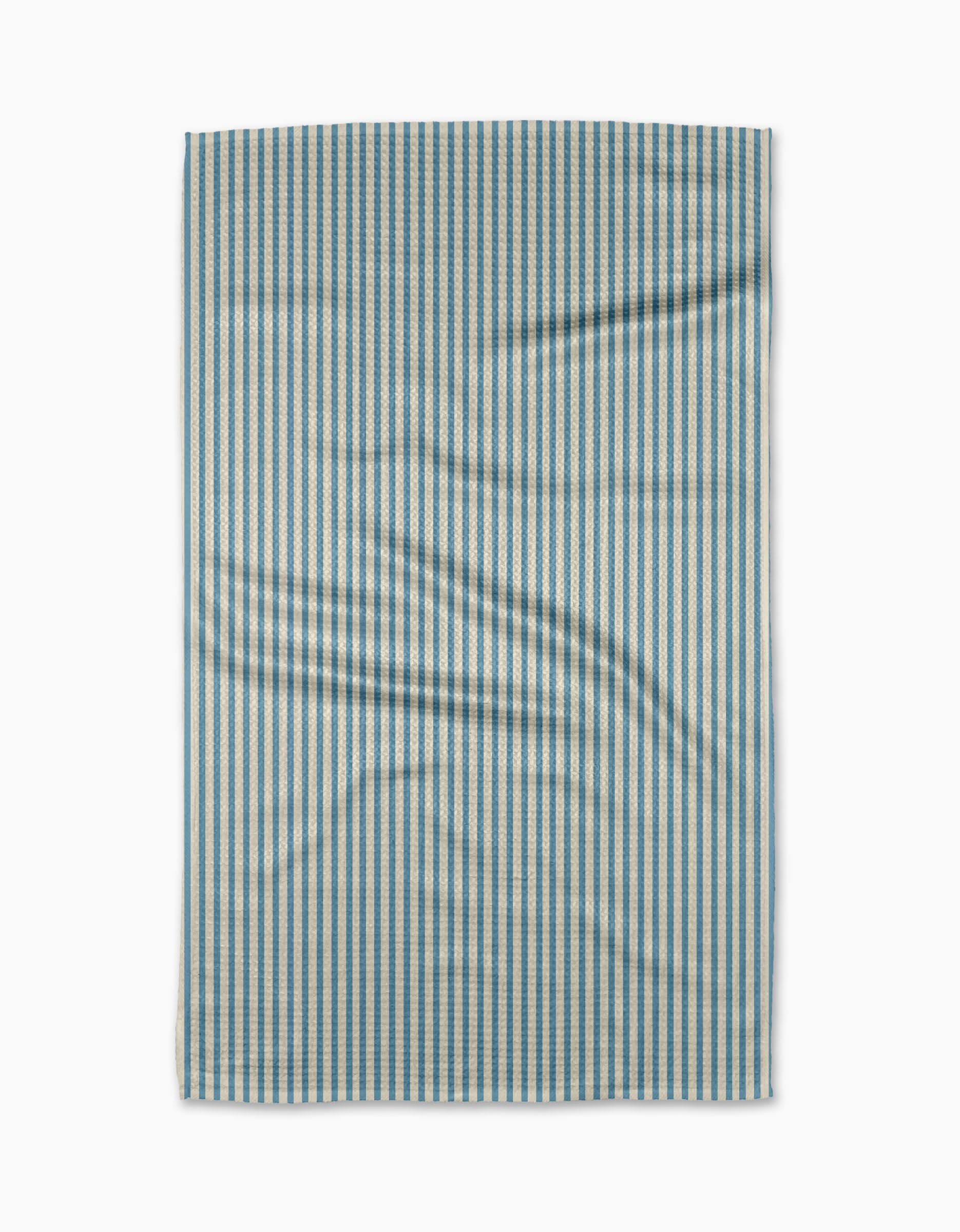 The Clean Slate tea towel by Susan Heid is rectangular, made from recycled materials, with thin blue and white vertical stripes and a slightly wrinkled texture, shown against a white background.