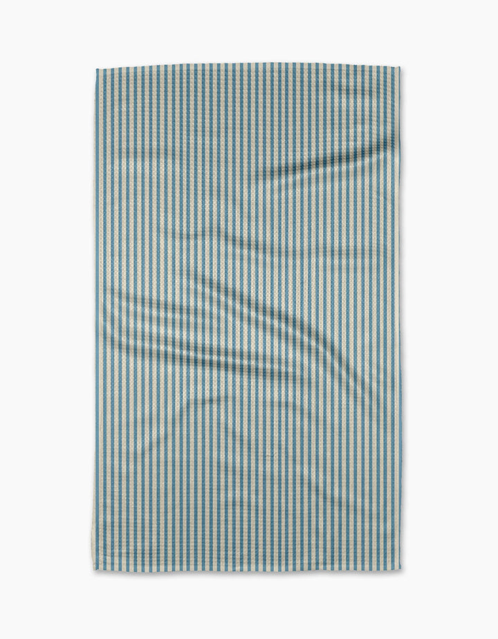 The Clean Slate tea towel by Susan Heid is rectangular, made from recycled materials, with thin blue and white vertical stripes and a slightly wrinkled texture, shown against a white background.