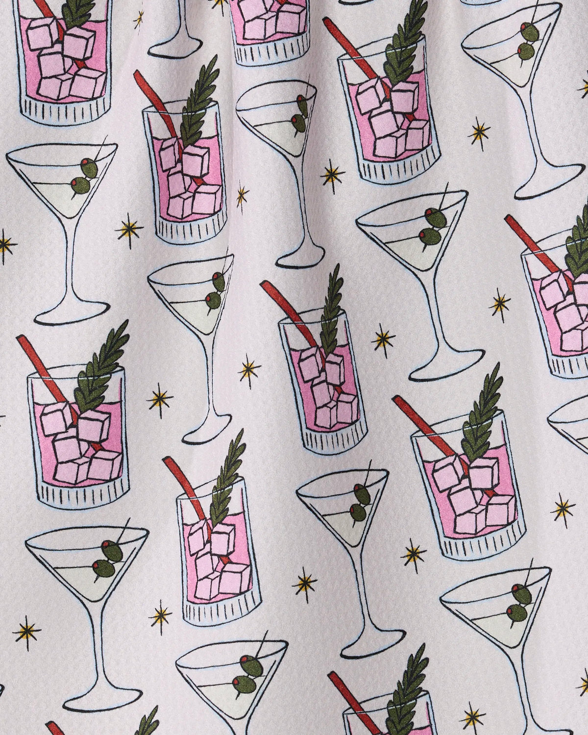 Introducing Geometry’s “Cocktail Countdown” tea towel—an ultra-absorbent kitchen essential crafted from recycled materials. Featuring a playful pattern of illustrated martini glasses with olives and old fashioned glasses filled with pink drinks, ice, and garnishes, all scattered with small gold stars on a crisp white background, this tea towel adds both sustainable style and function to your kitchen.