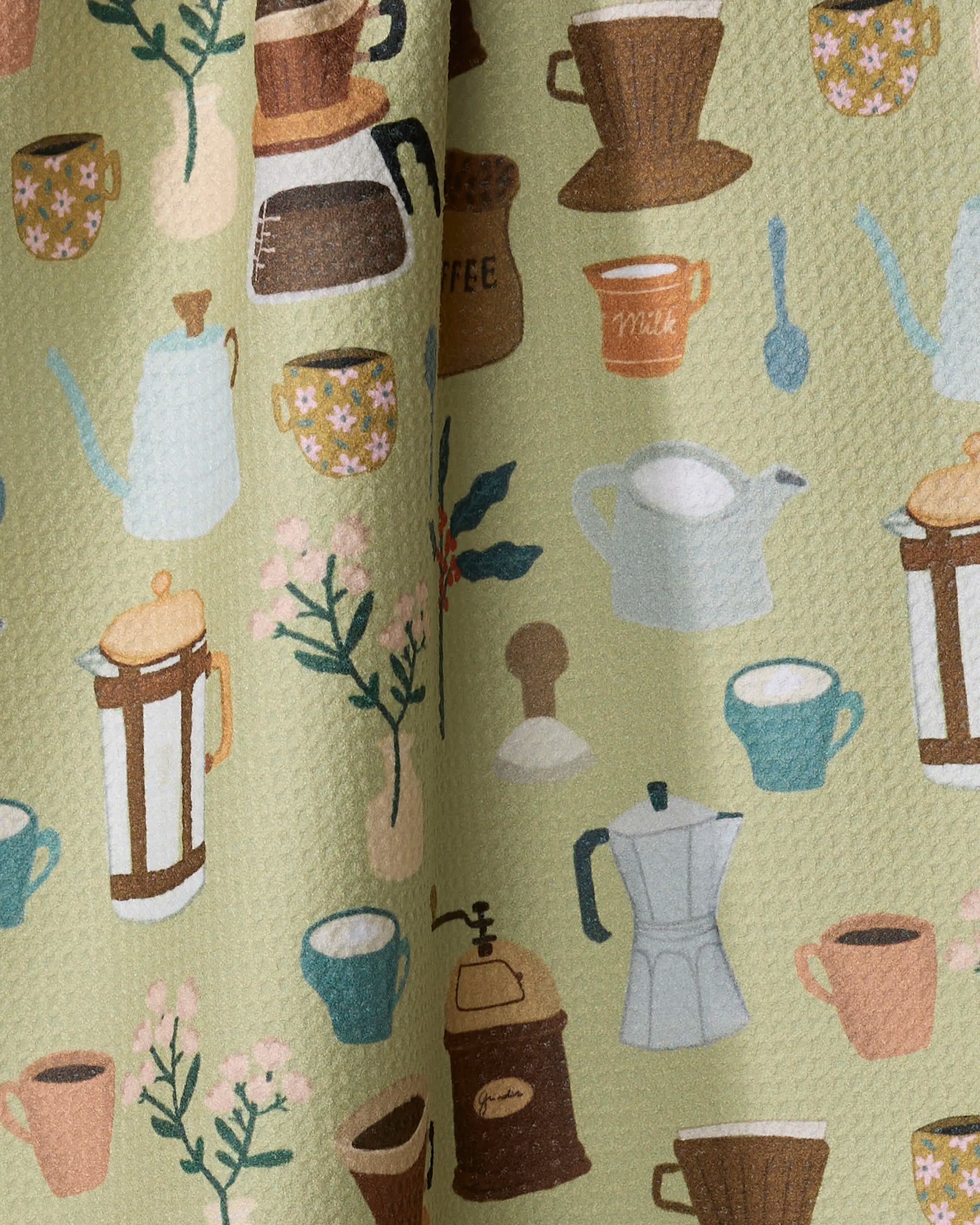 The Coffee Lover tea towel by Cottonflower Studio features a green textured fabric with pastel coffee pots, mugs, grinders, flowers, and jars. This vintage-style kitchen towel is crafted from recycled materials.