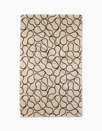 The Gerdadzy Coffee Swirl rug is a beige rectangular piece made from recycled materials, featuring an abstract wavy brown line pattern across its surface.