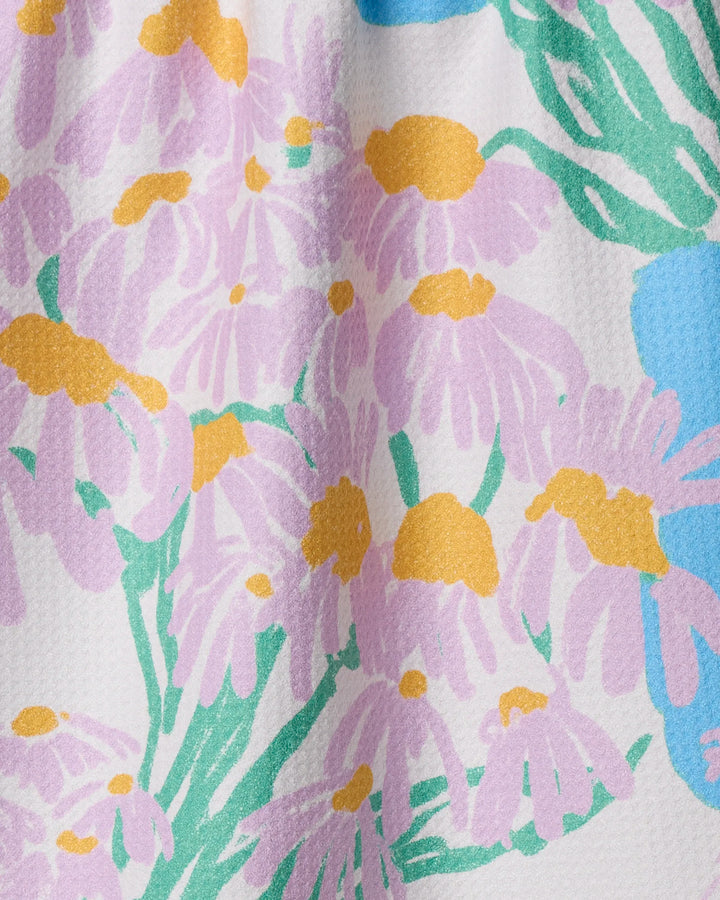 Close-up of Geometry’s Colette kitchen towel, featuring a pastel floral pattern with light purple flowers, yellow centers, and green leaves on a white background. The textured fabric is eco-friendly and highly absorbent—perfect for drying dishes.