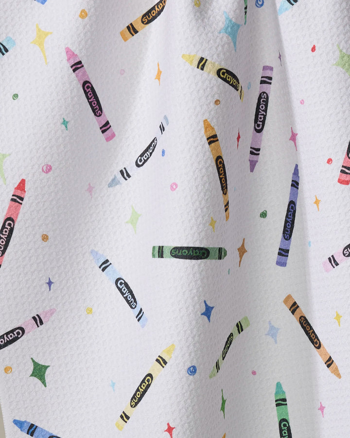 The "Colored Crayons" tea towel by Vaishali Design Studio has a white textured surface decorated with vibrant crayon illustrations and playful stars, made from quick-drying fabric for a fun and practical addition to your kitchen.
