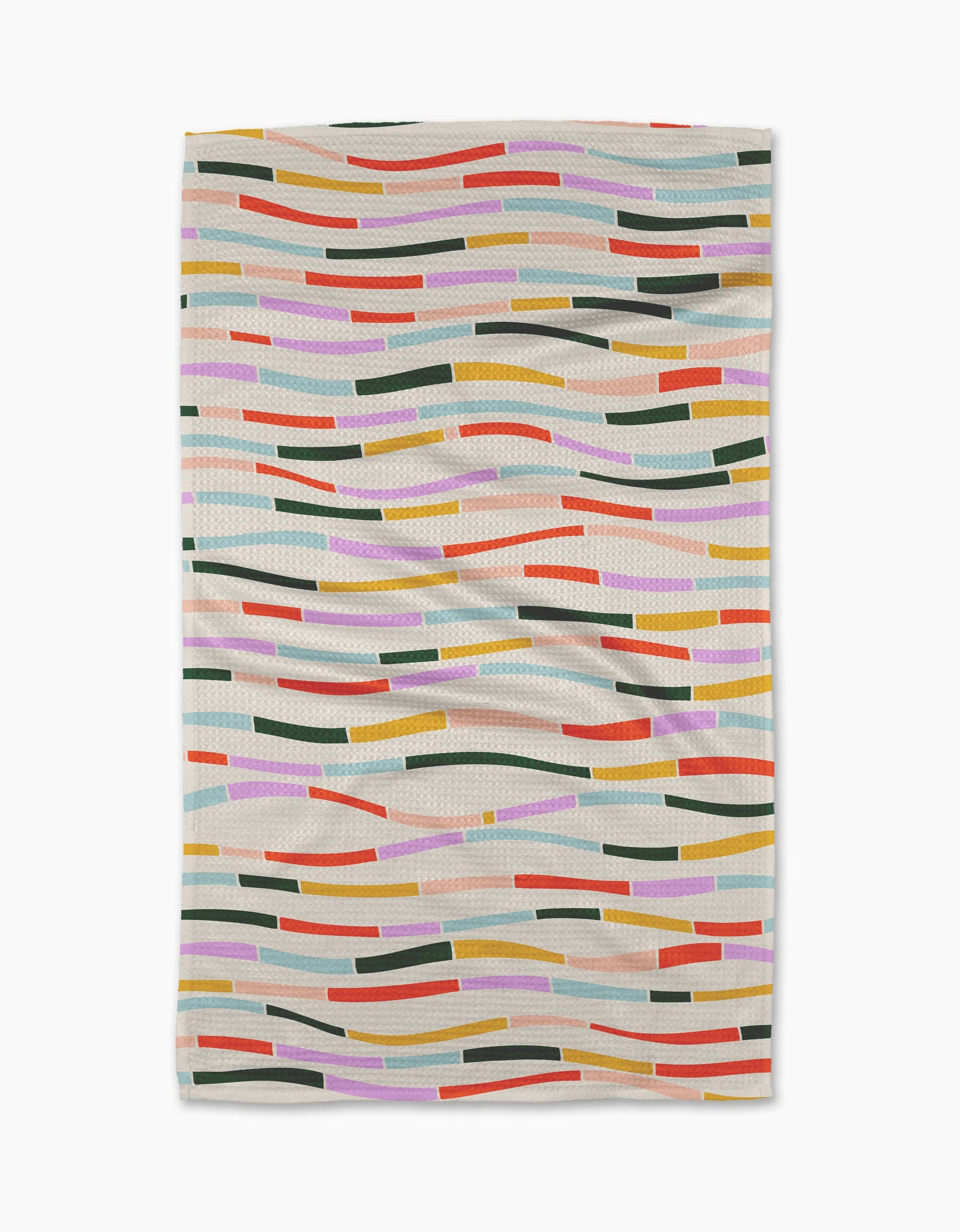 The Geometry Colorful Currents blanket features wavy, multicolored lines and rectangles in orange, pink, green, yellow, blue, and red on a light beige background. Its crafted from post-consumer recycled materials.
