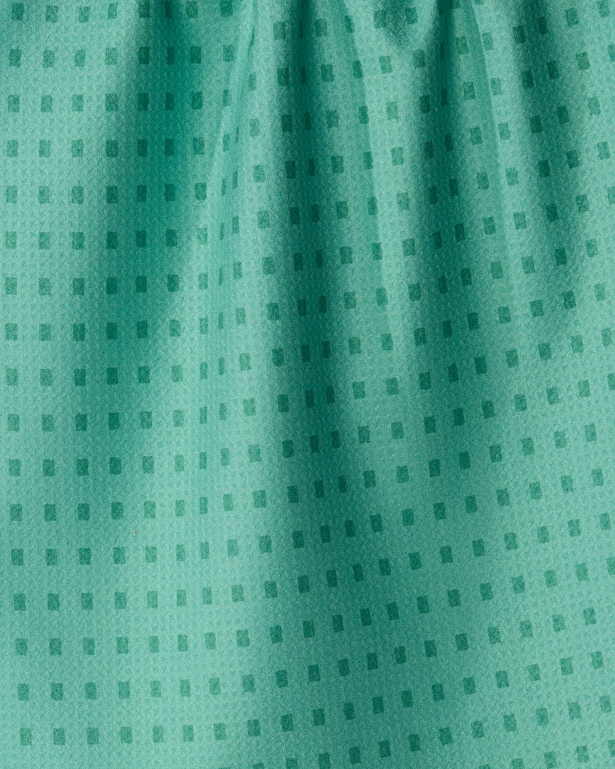 Confetti Tiles by Geometry features green fabric with a subtle, small square pattern and gentle folds that create soft shadows, giving the material a textured and slightly shiny appearance—ideal for an eco-friendly kitchen towel that perfectly blends style with sustainability.