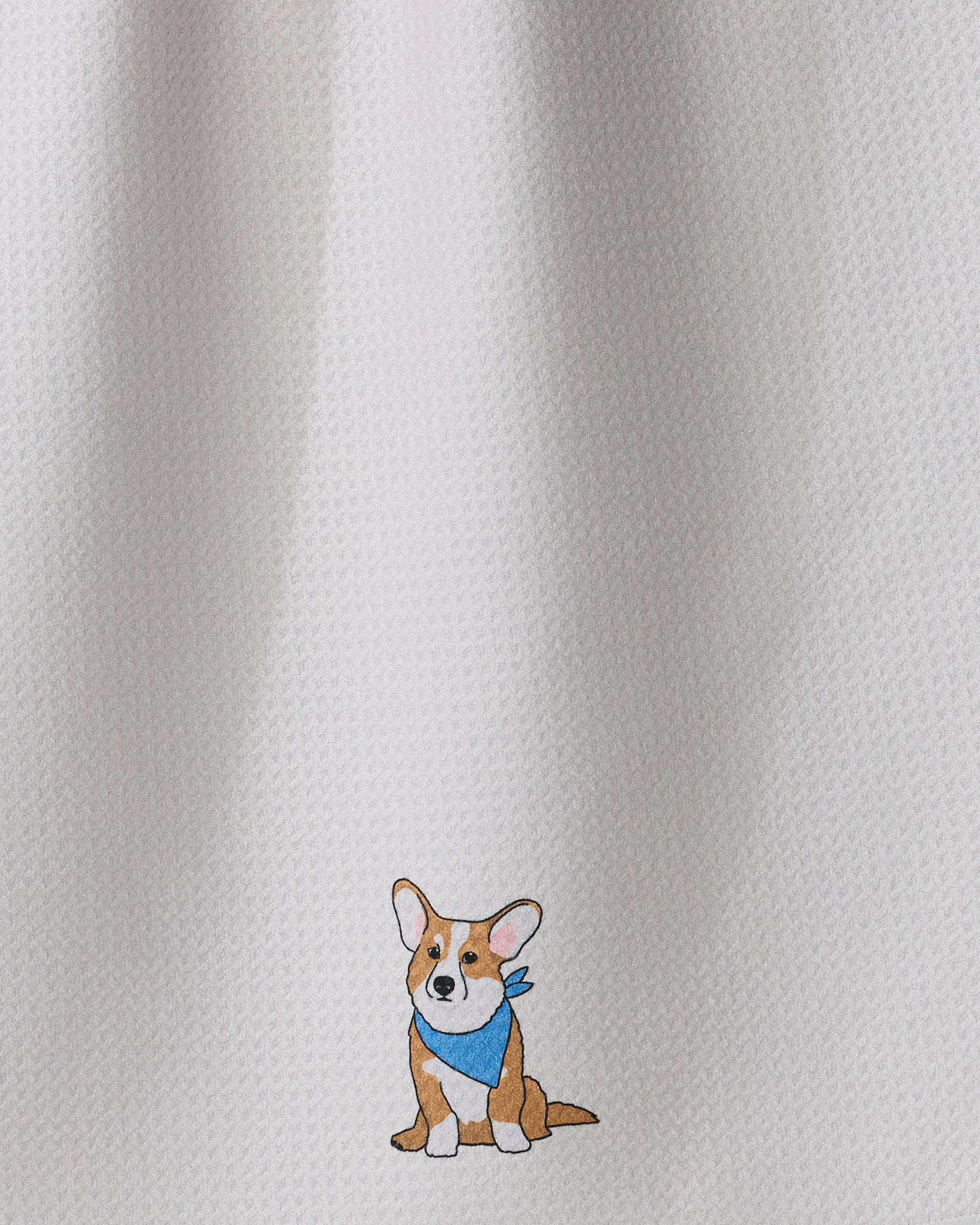 A small illustration of a brown and white corgi wearing a blue bandana is centered near the bottom of Geometry’s “Corgi Charm” tea towel. Crafted from recycled materials, this textured white kitchen towel combines sustainability with irresistible charm.